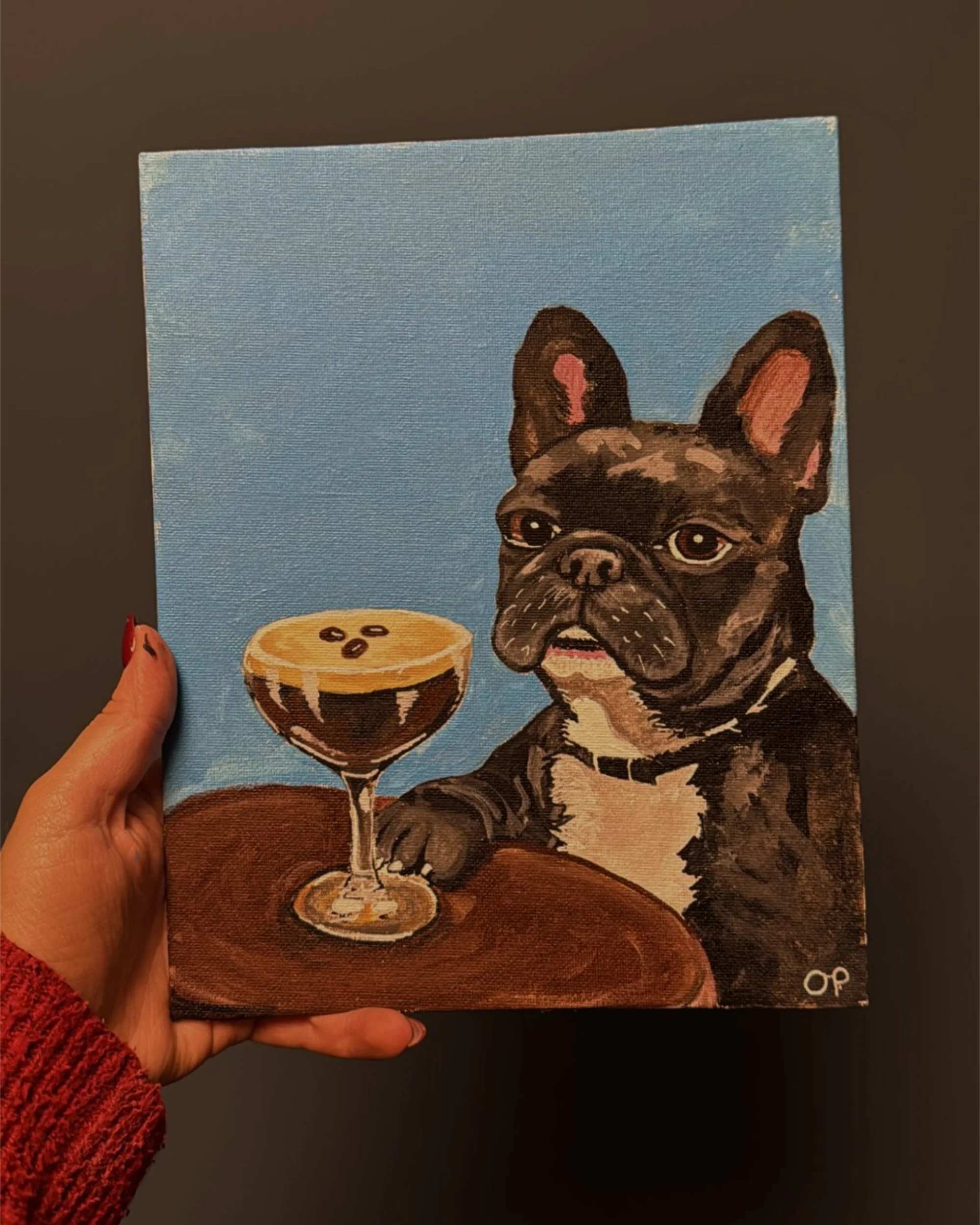 Hand holding a custom pet portrait of a French Bulldog with an espresso martini, showing the size of an 8×10 inch canvas