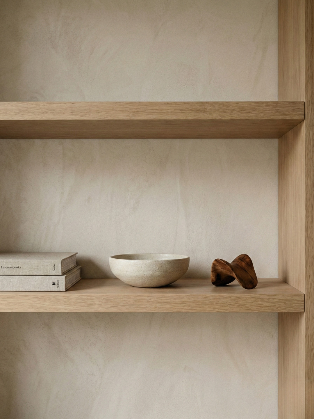 A minimal styled wooden shelf with books and a ceramic bowl