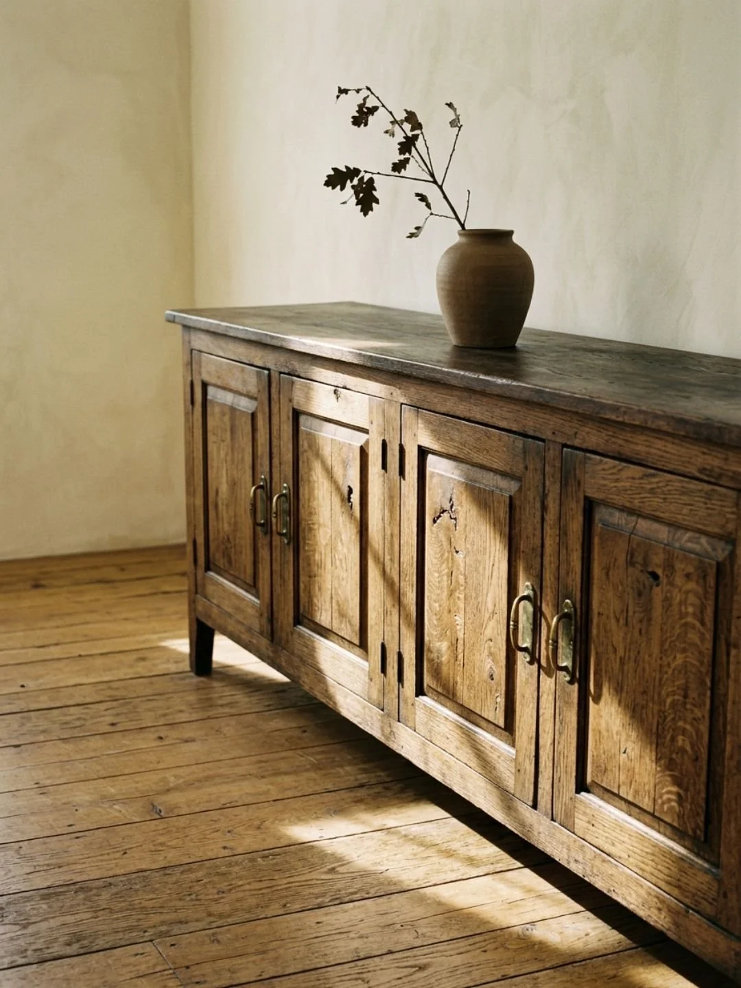 sideboard with a vase on top holding a branch