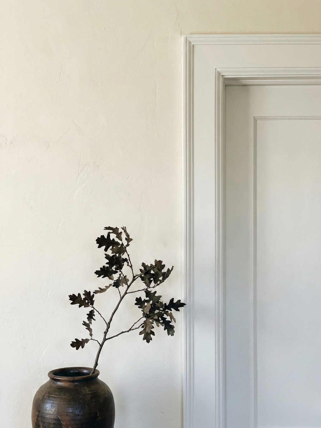 Close-up of a door frame painted in crisp white contrasting the creme wall