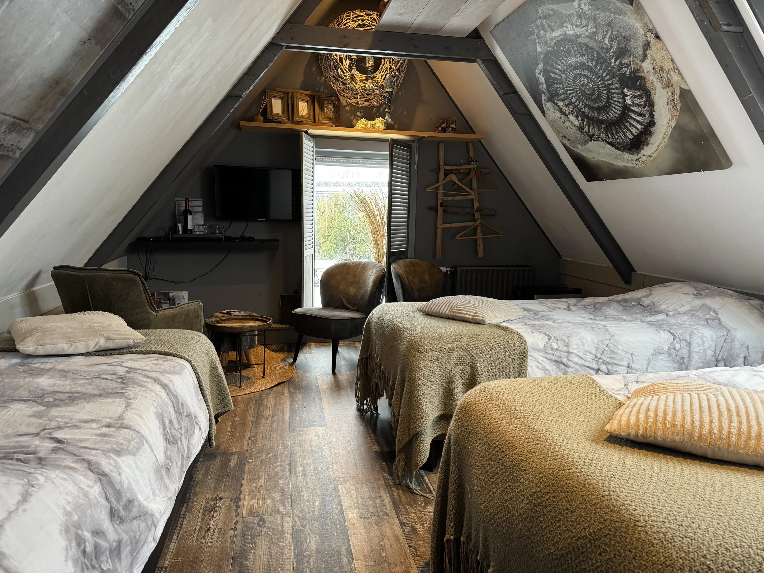 Ruime 3-persoonskamer op de bovenverdieping van de B&B met drie eenpersoonsbedden, zithoek en schuine wanden, sfeervol ingericht met warme materialen en veel daglicht.