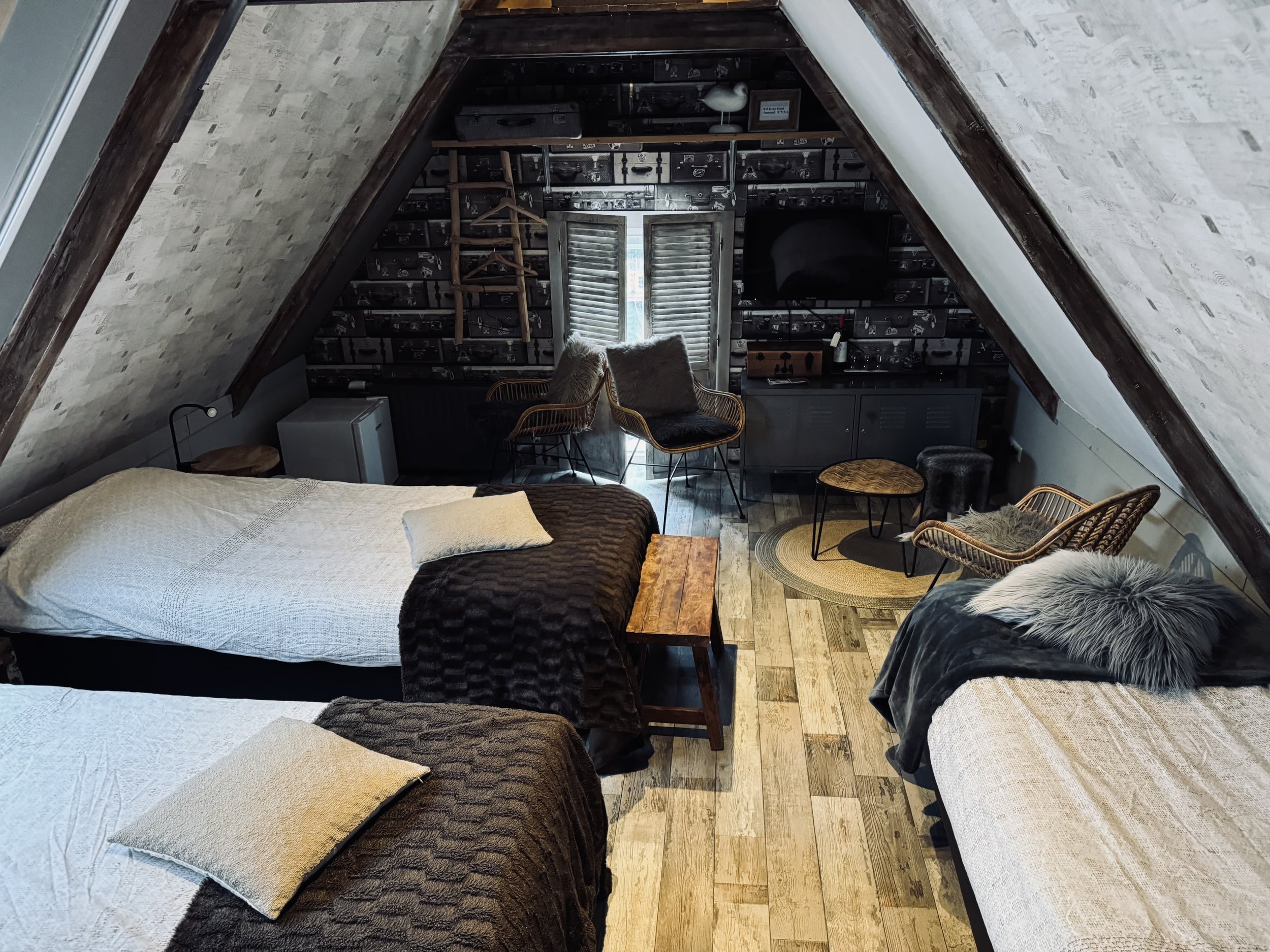 Sfeervolle 3-persoonskamer op de bovenverdieping van de B&B met drie eenpersoonsbedden, zithoek en karakteristieke schuine wanden. Warm ingericht met natuurlijke materialen, houten vloer en veel licht voor een comfortabele en rustige overnachting.