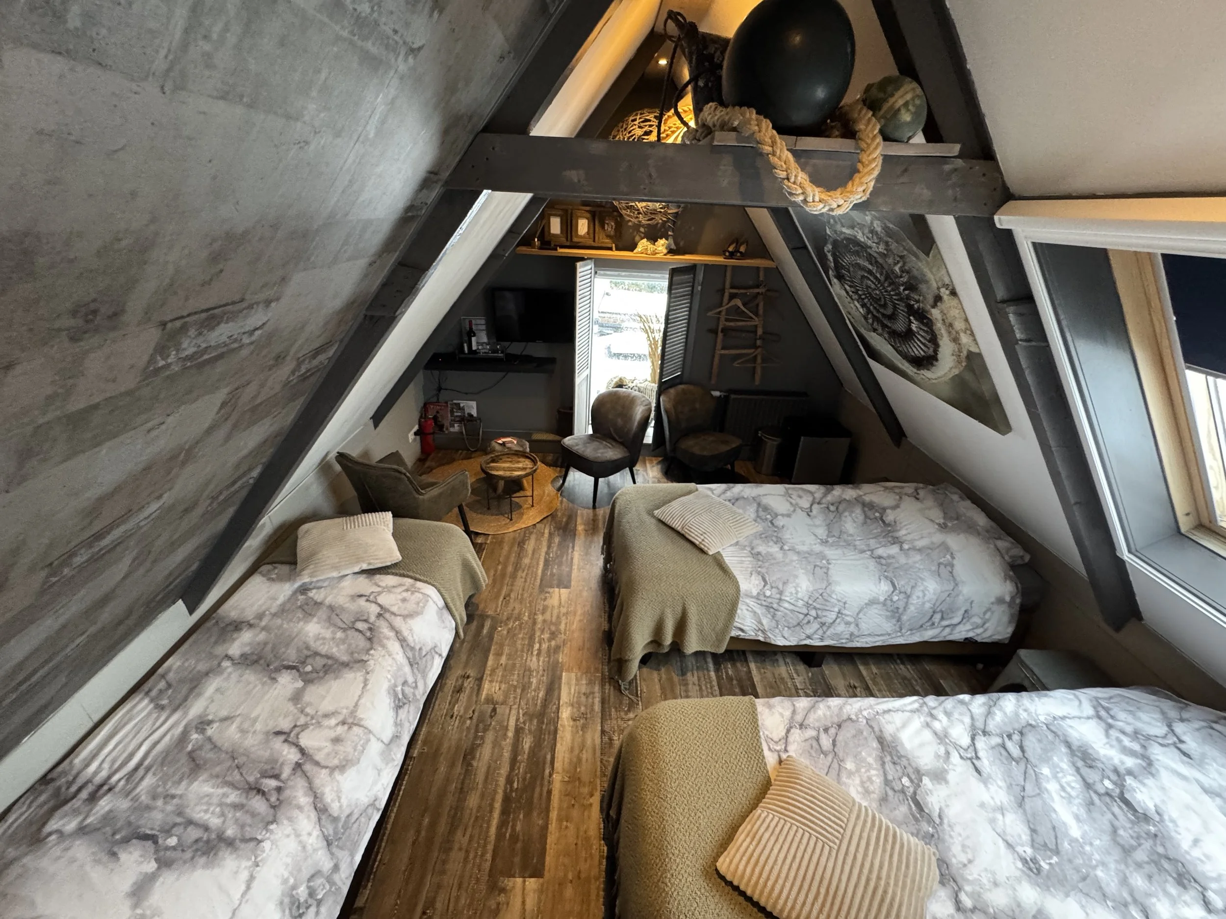 Sfeervolle 3-persoonskamer op de bovenverdieping van de B&B met drie eenpersoonsbedden, schuine wanden houten vloer en warme inrichting.