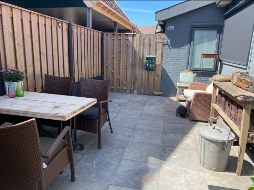 Afgeschermde buitenzitplaats bij het appartement van de B&B met eettafel en stoelen, een rustige plek om buiten te zitten en te genieten van privacy en frisse lucht.