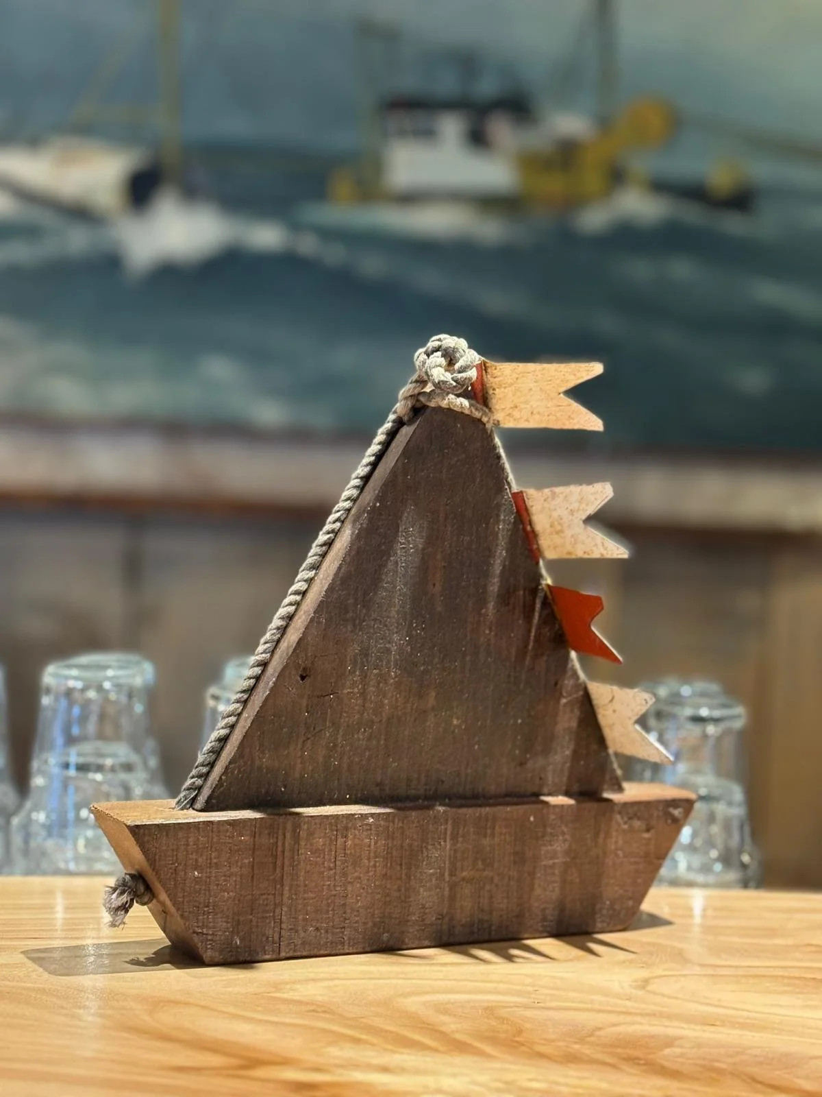 een klein houten bootje op een tafel met een andere foto op de achtergrond.