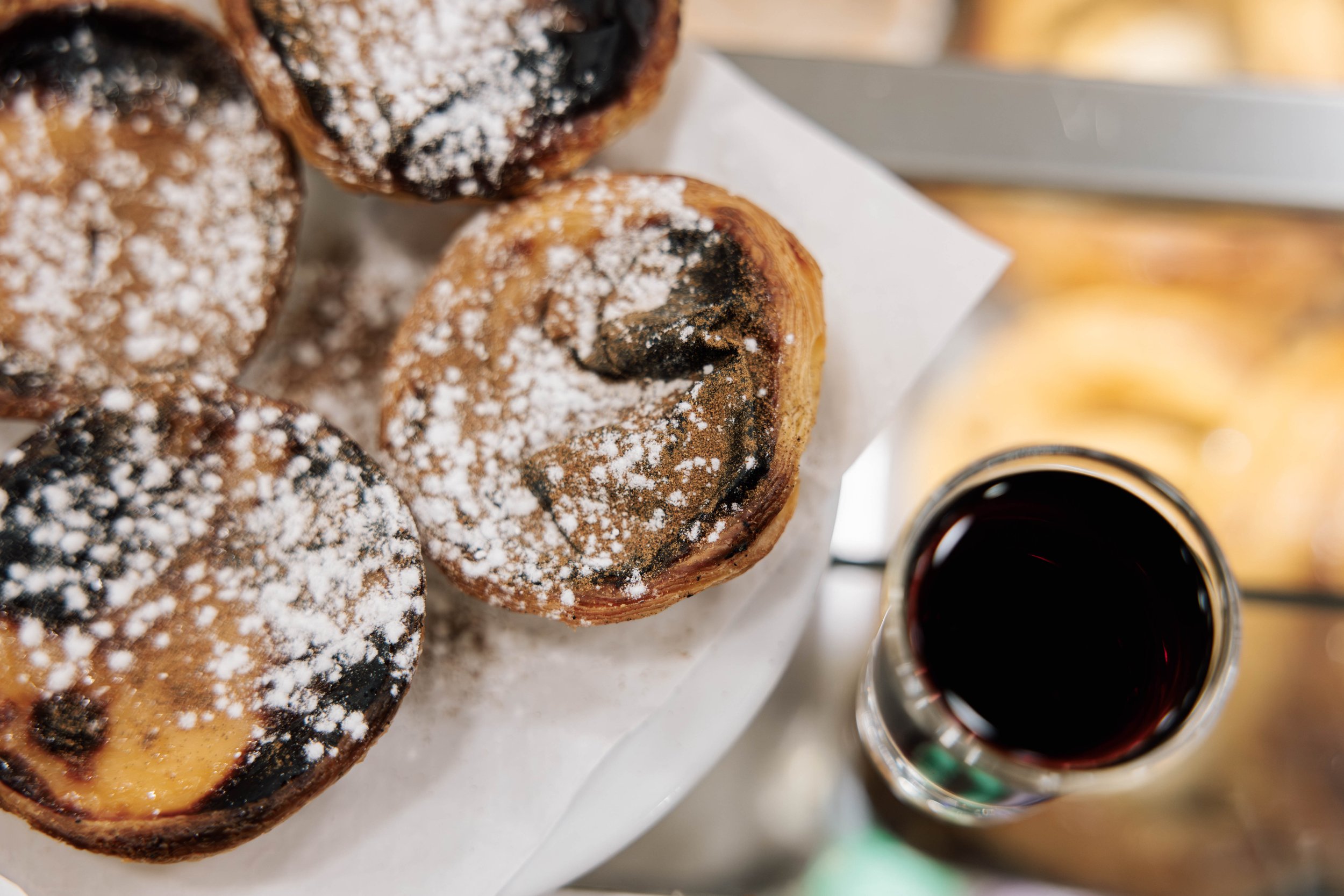 Close-up of grilled cinnamon rolls dusted with powdered sugar, served with a cup of coffee on the side.