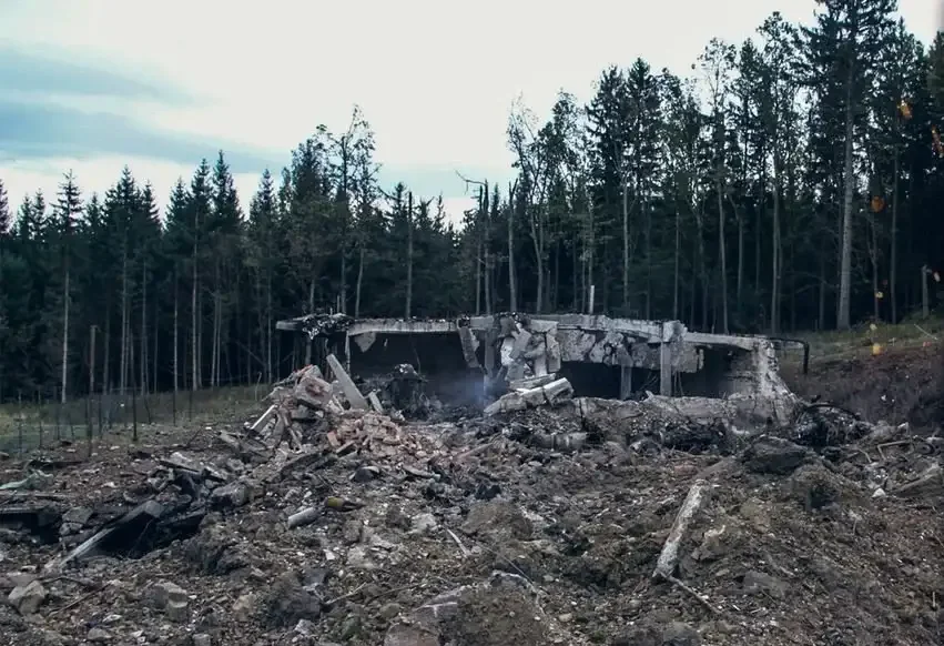 Destroyed rubble and remains of a structure in a forested area after an explosion or disaster.
