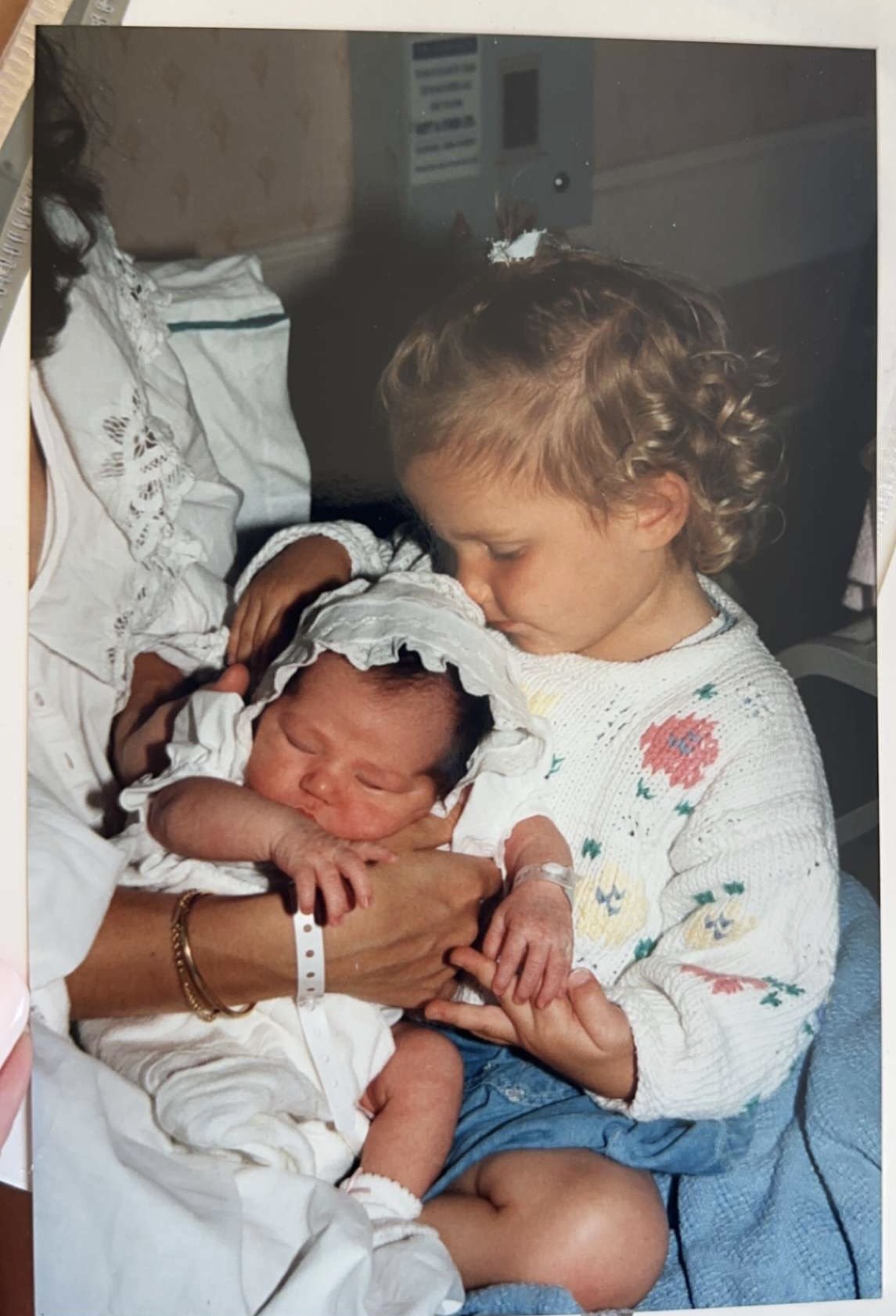A young girl holding a newborn baby in a hospital room.