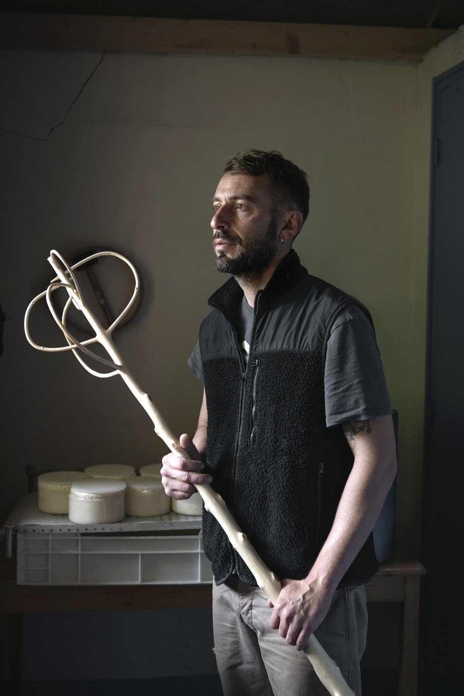 Un homme tient un bâton de chasse en forme d'illustre, dans une pièce éclairée doucement.