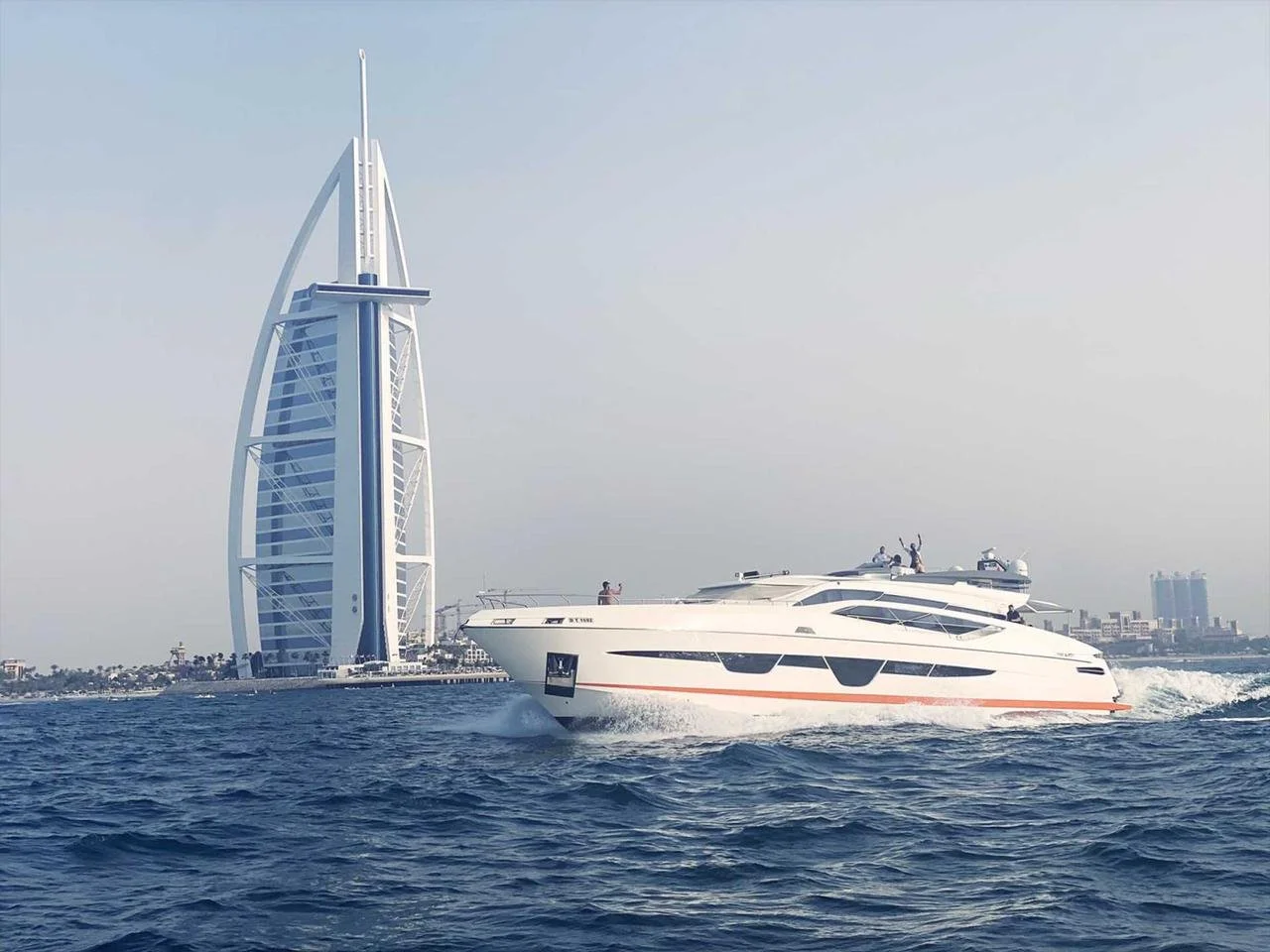 A luxury yacht speeding across the water in front of the Burj Al Arab hotel in Dubai.