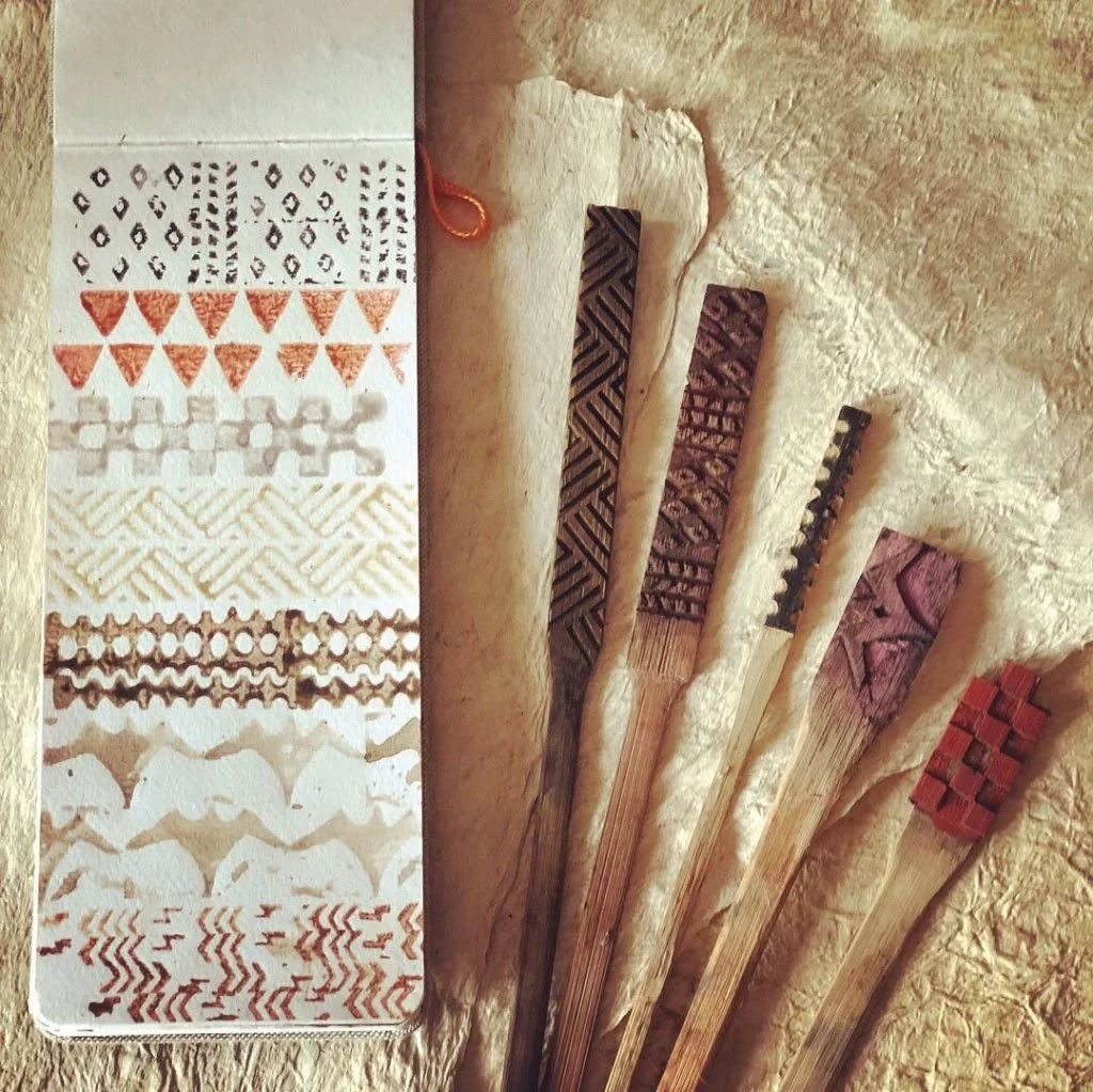 A sheet of temporary tattoo designs with various patterns and six wooden sticks with carved patterns.