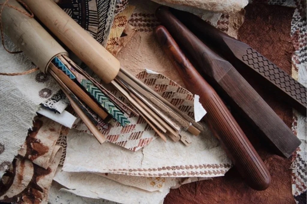 Assorted carved and decorated wooden stamps and rollers on fabric.