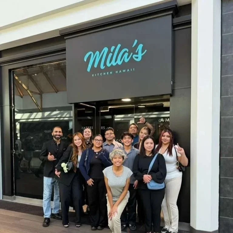 Group of people standing outside Milas Kitchen Hawaii restaurant, smiling and posing for the photo.