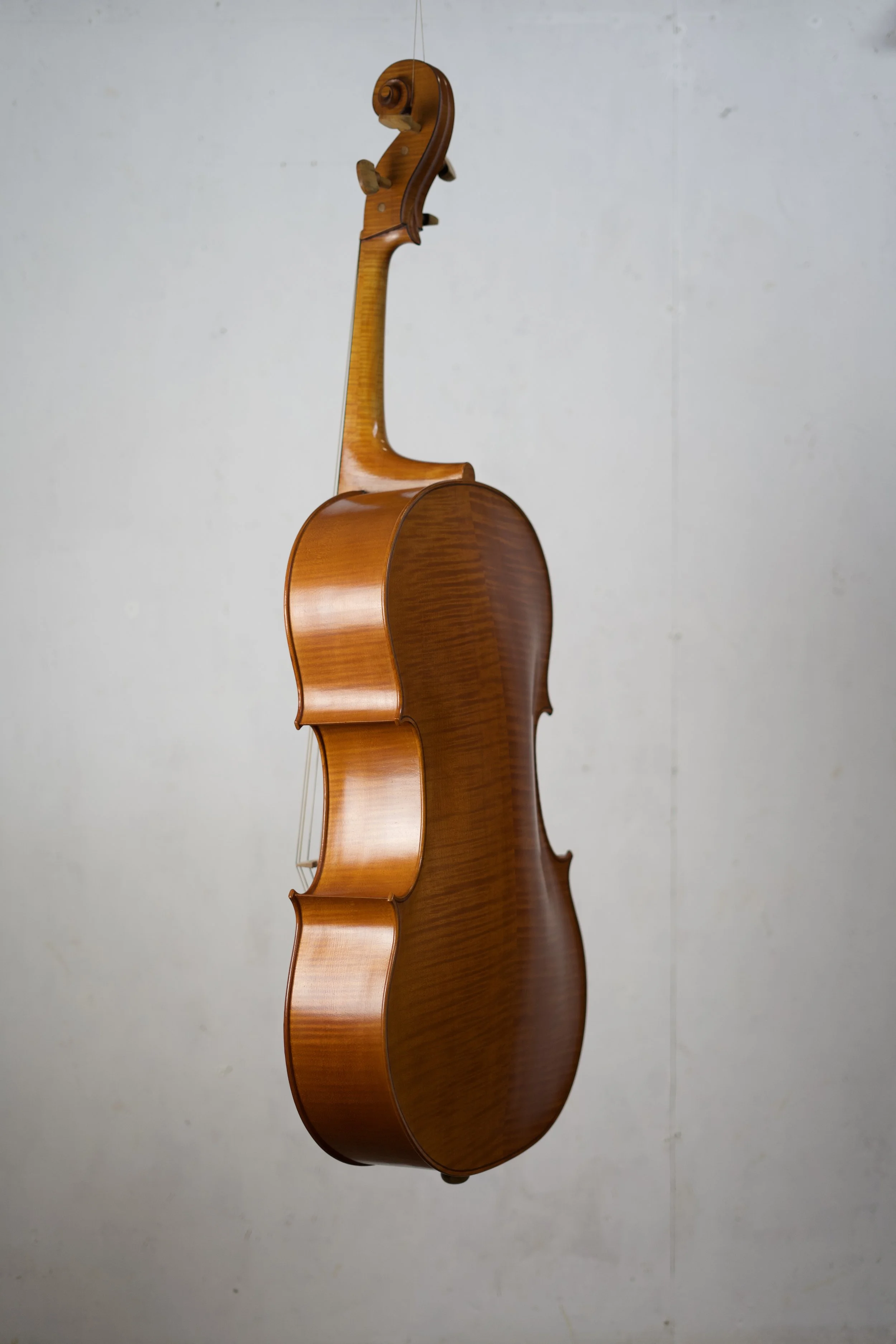 A wooden cello hanging on a wall.