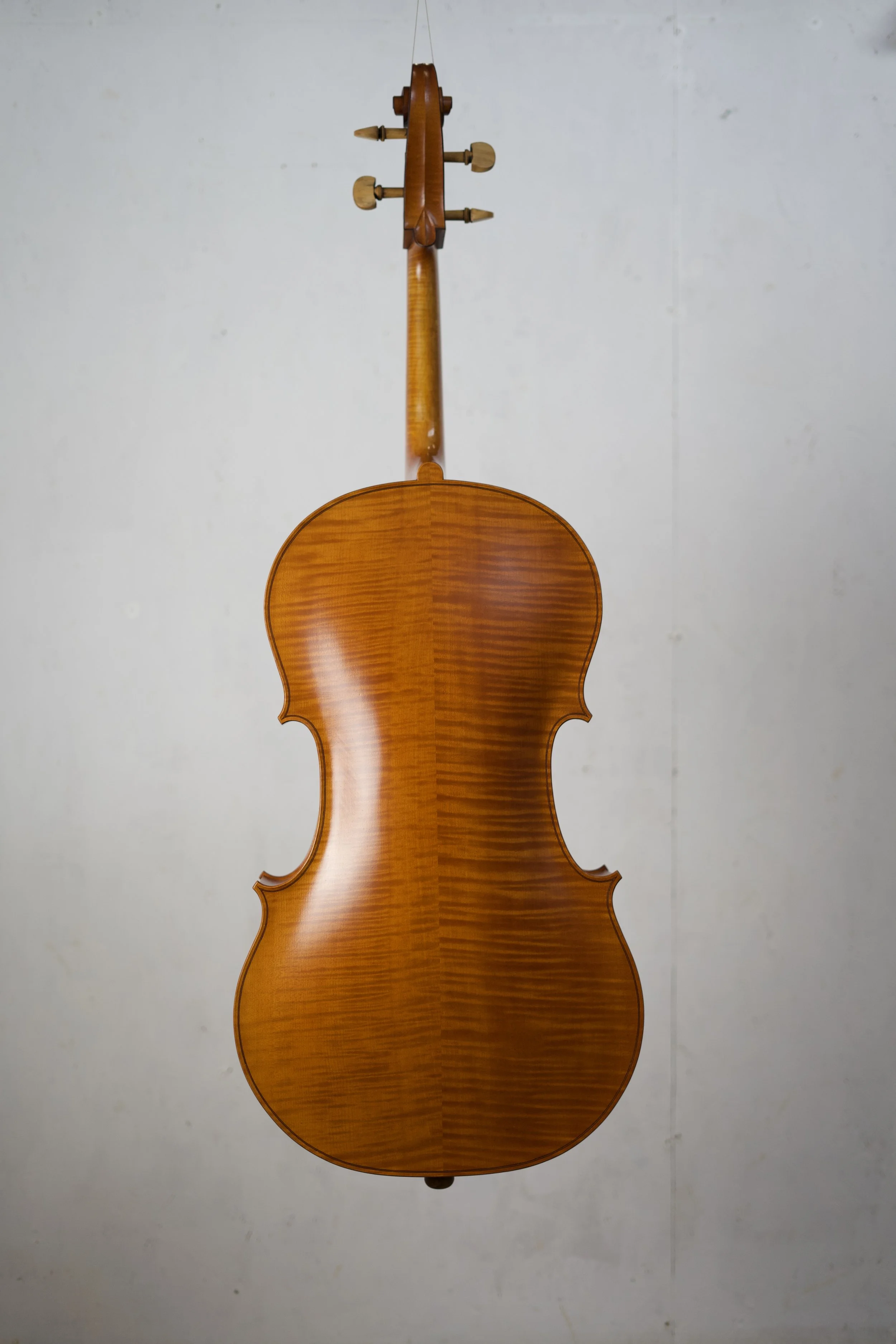 Back of a wooden violin hanging against a plain white wall.