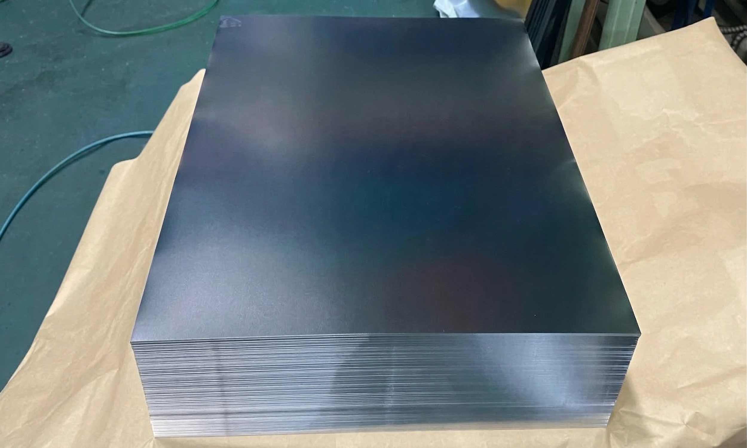 Stack of metal sheets on a table, with paper and wires nearby.