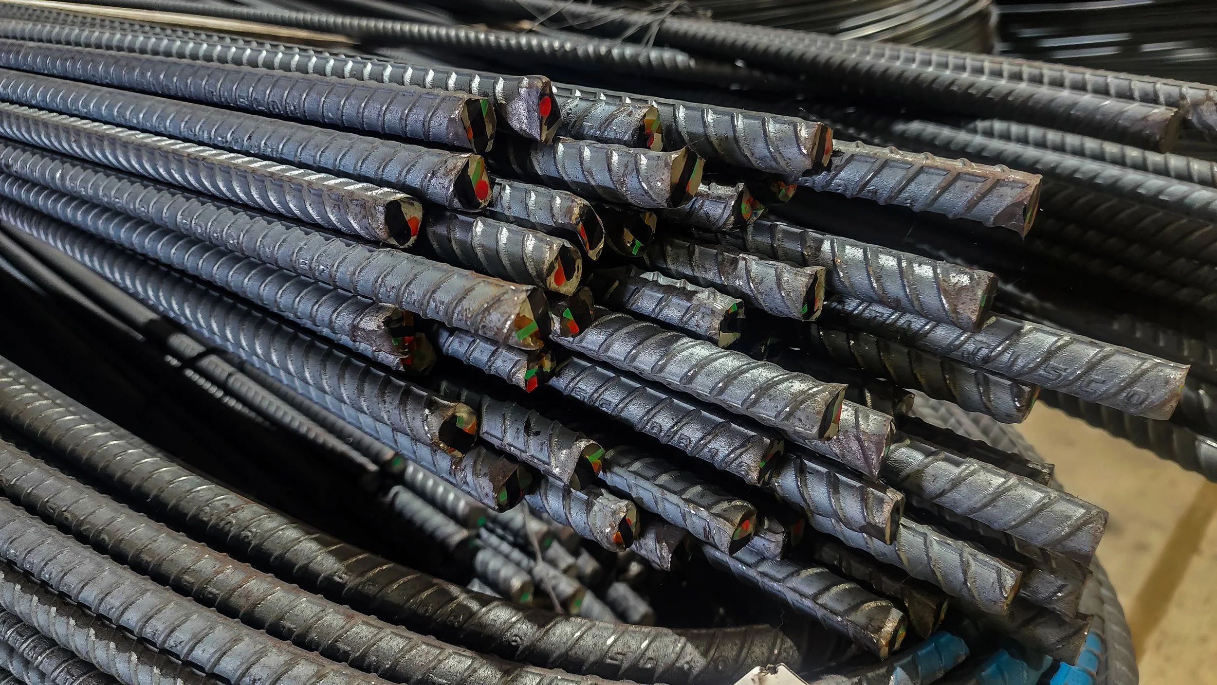 Stack of rebar steel rods for construction, showing the textured surface and colored markings.