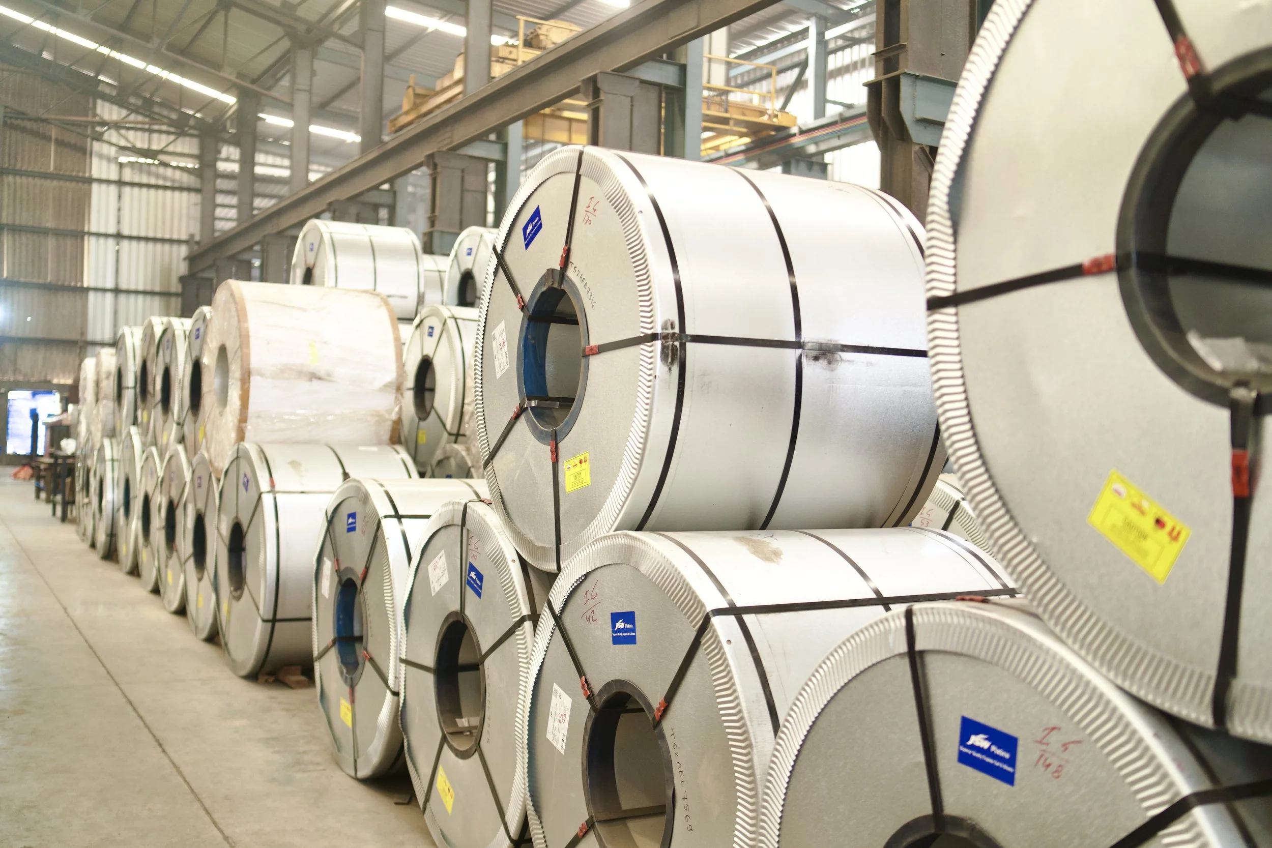 Rows of large steel coils stored in a warehouse.