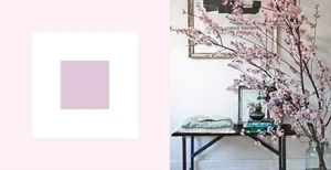 Decorative pink cherry blossom branch arrangement on a wall with a small table holding books and decorative objects