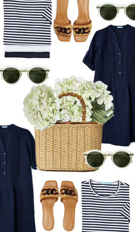 Flat lay of a navy blue dress, striped navy and white t-shirt, tan slides, round sunglasses with green lenses, a wicker basket, and a bouquet of white hydrangeas.