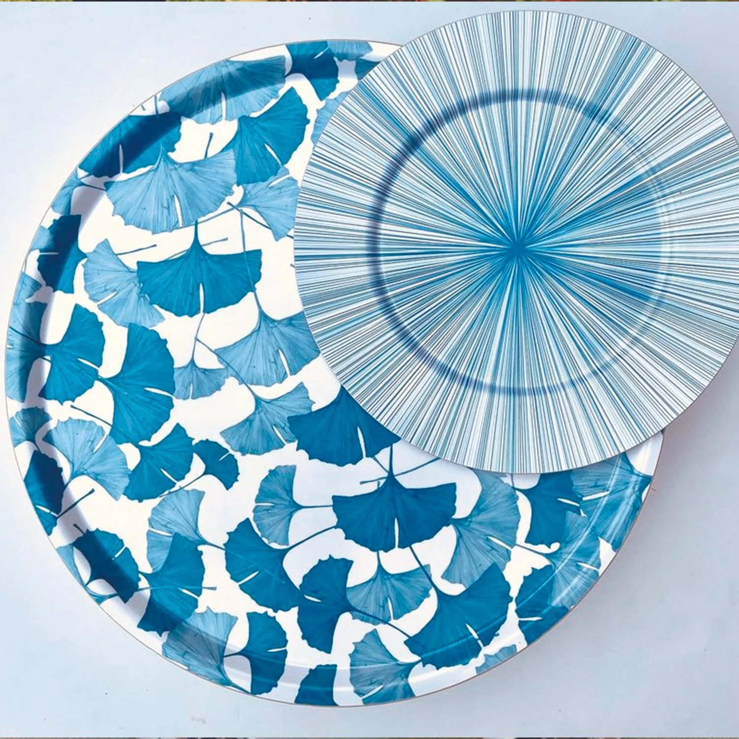 Blue and white paper plate with ginkgo leaf pattern and a matching paper plate with a radiating line design.