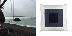 Beach with rocks and calm water on a cloudy day, side view with a tree and a distant structure
