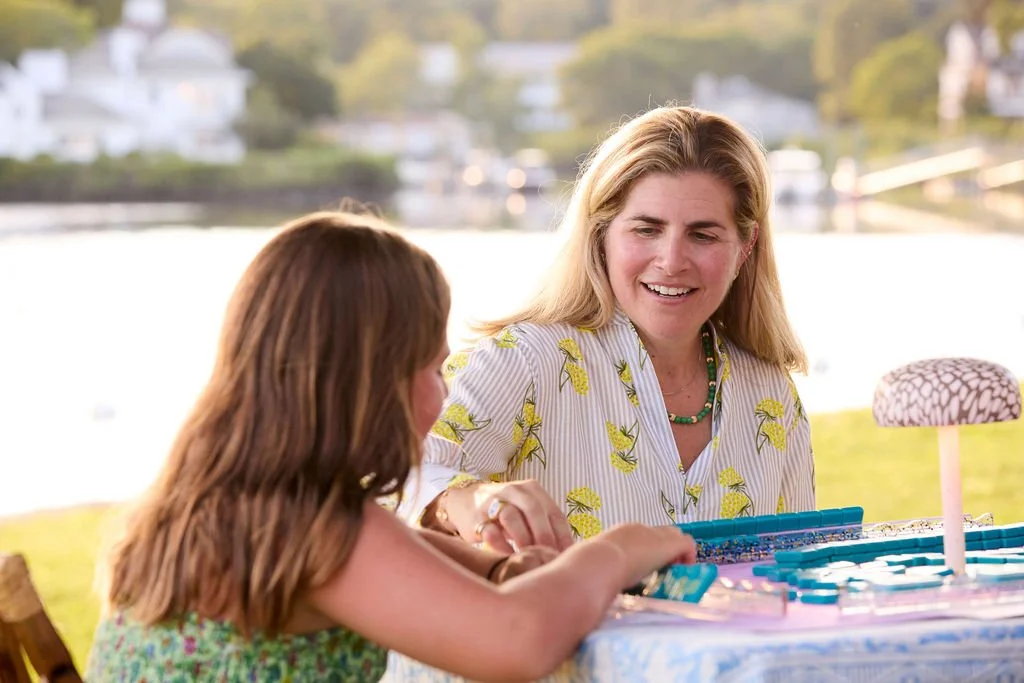 Woman playing a game with a girl outdoors near a lake with houses in the background.