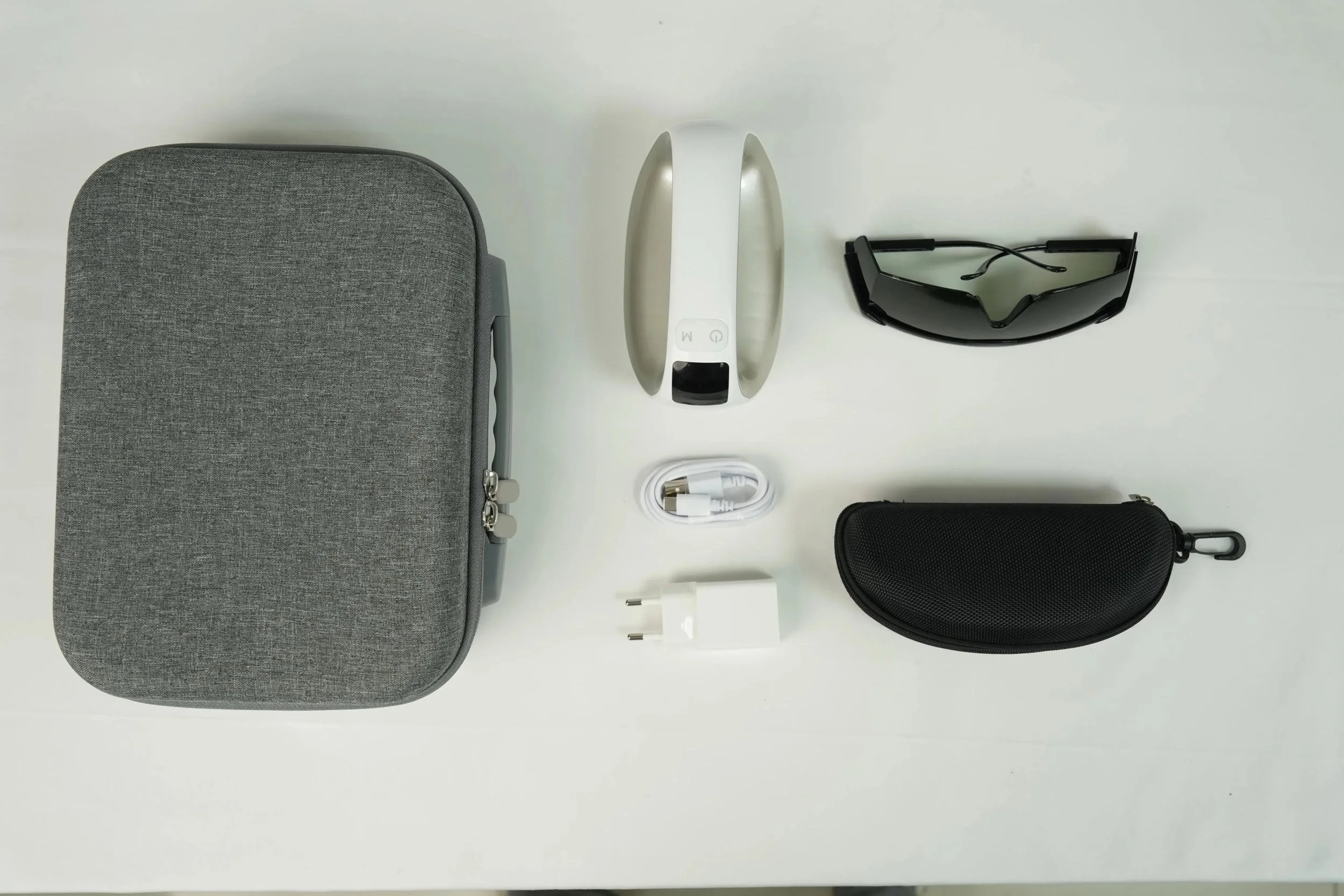 &RECOVER Case & Recovery Kit flat-lay: a gray fabric carrying case, the white &RECOVER laser handset, a charging cable, black laser safety glasses, and a black hard case, laid out on a white surface.