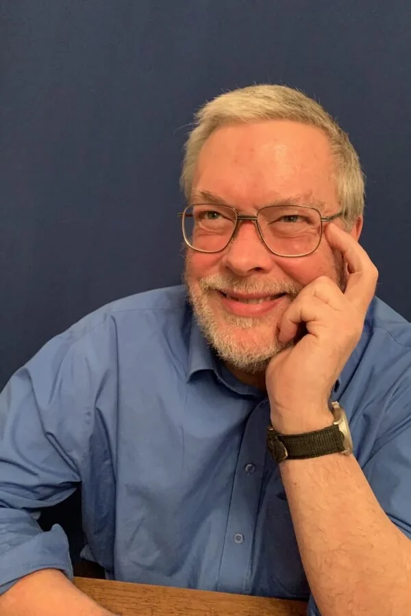 Photograph of Professor Harold Thimbleby smiling while leaning on a desk