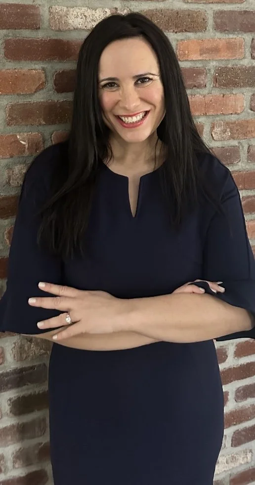 Rachel Belin standing in front of brick wall.