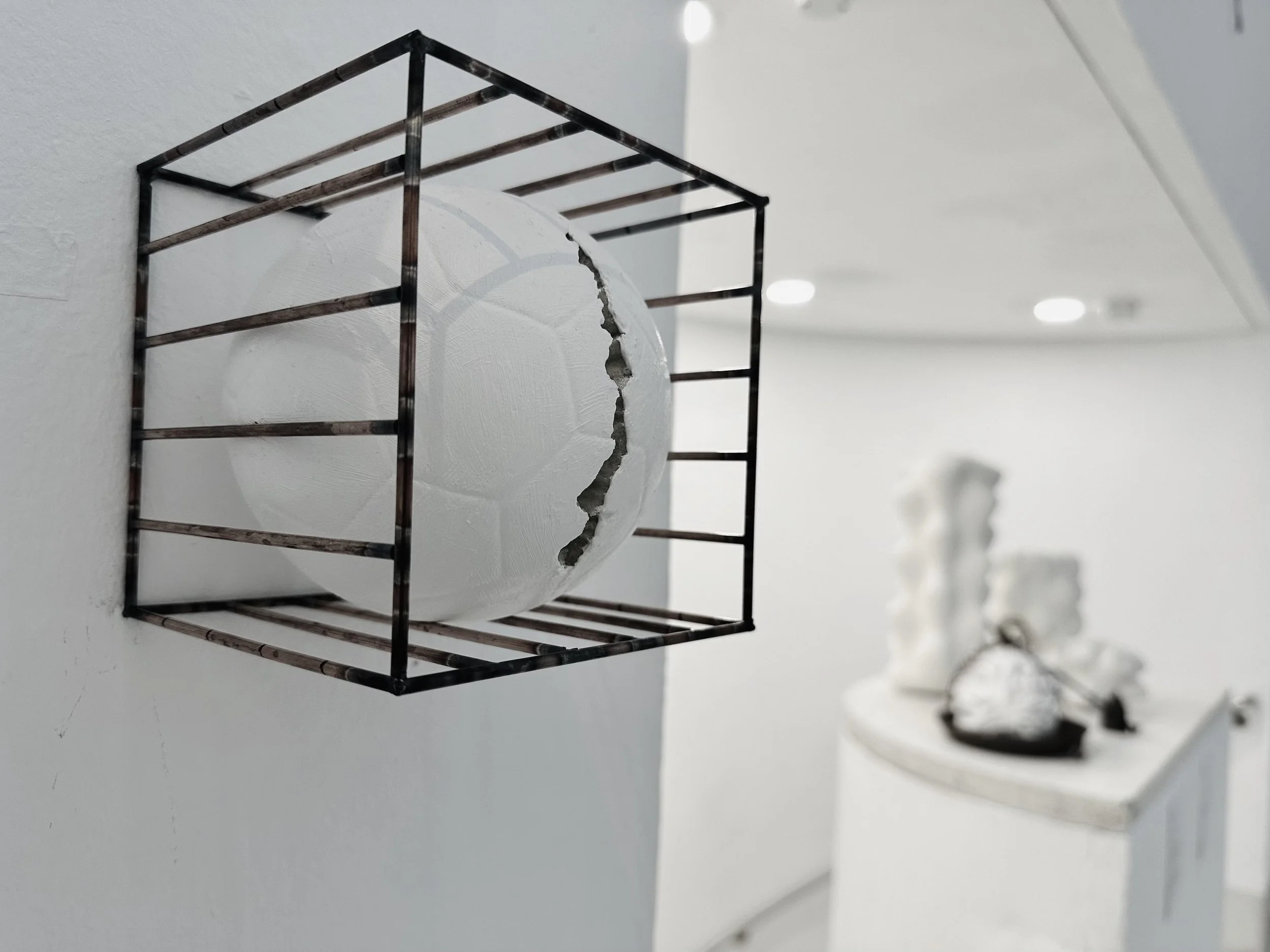 A metal rack mounted on a white wall with a broken white circular object behind it.