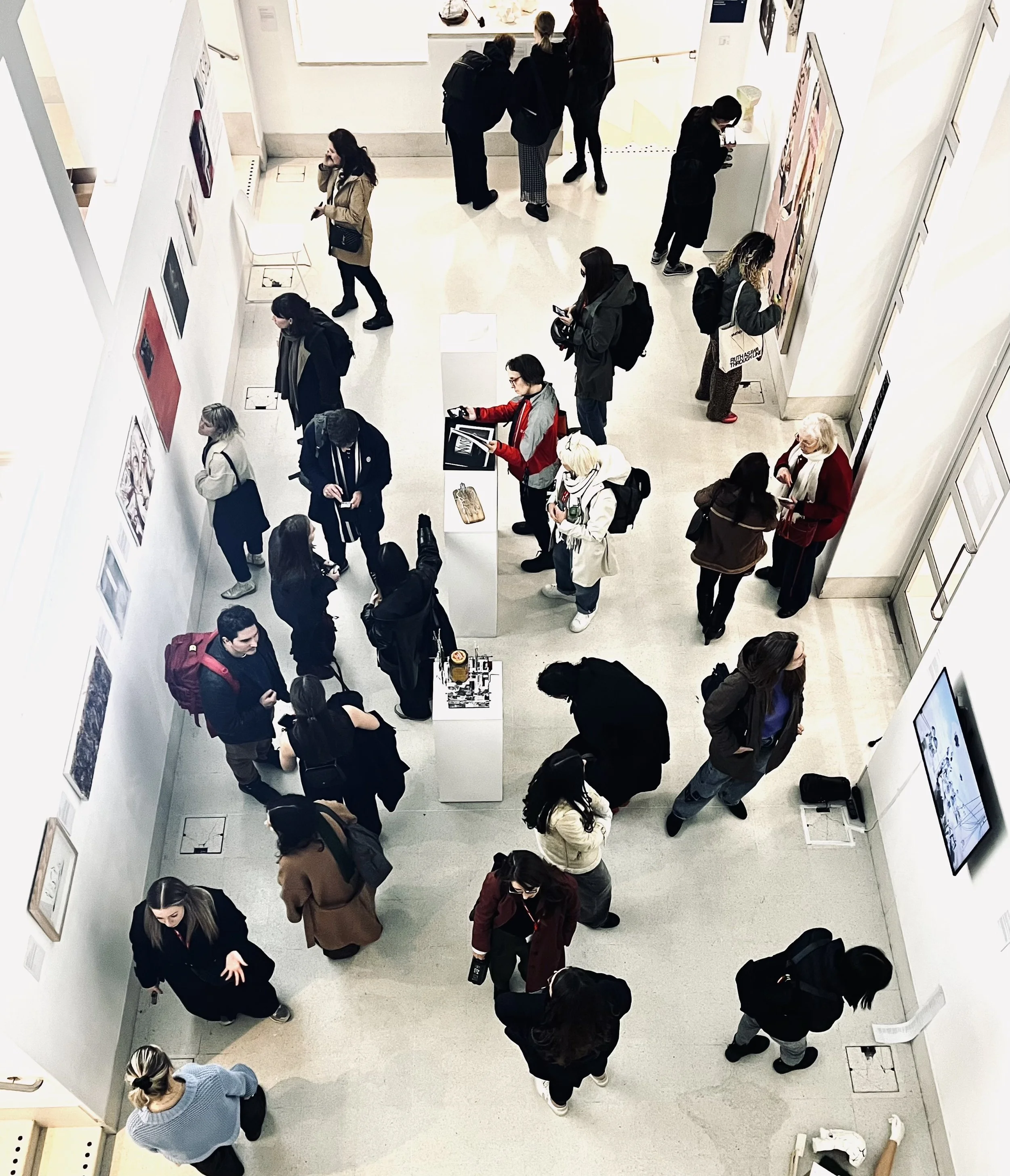 People viewing artwork and engaging with pieces on display in an art gallery.