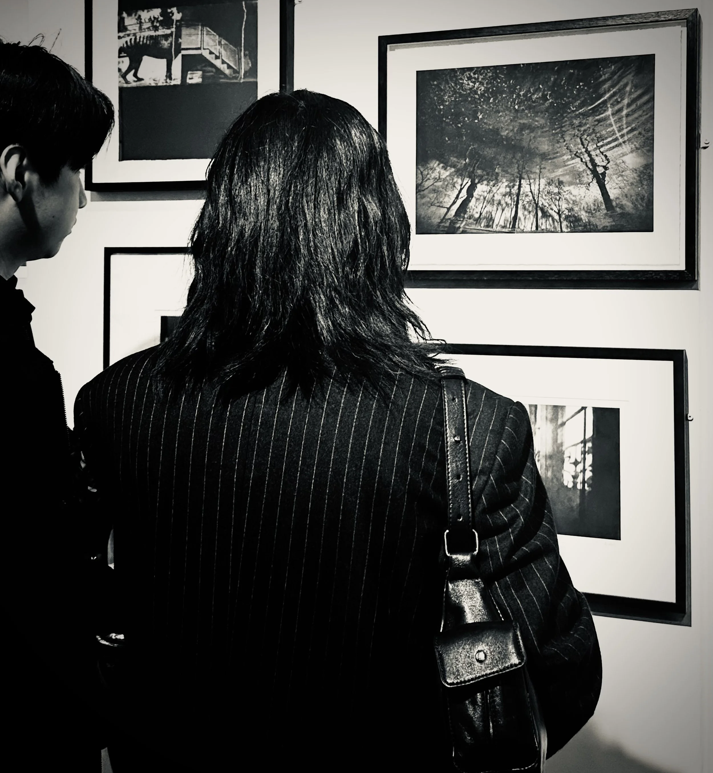 People viewing black and white photographs in an art gallery.