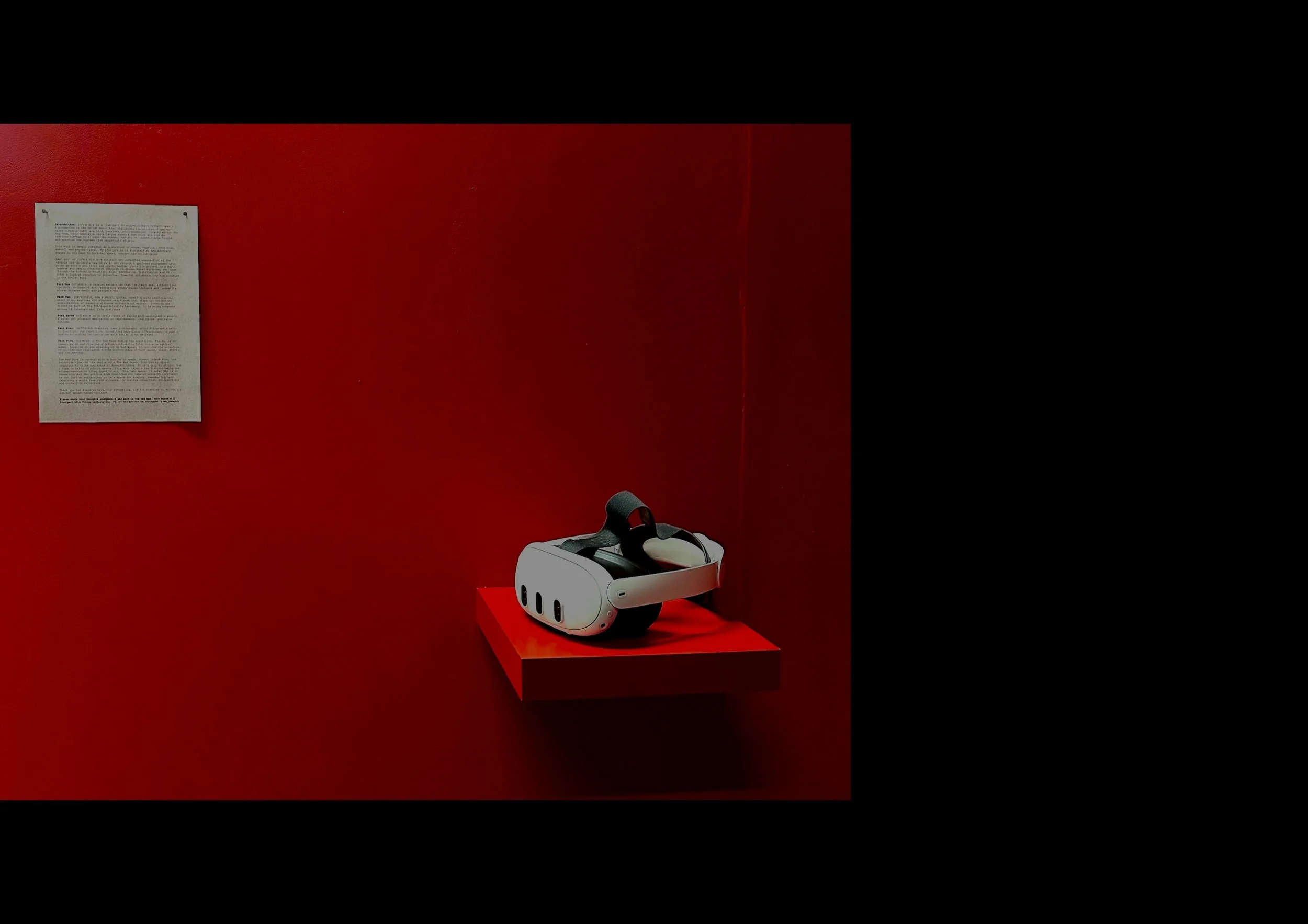 Virtual reality headset placed on a red stand in a dark room with a red wall and a white informational sheet on the wall.