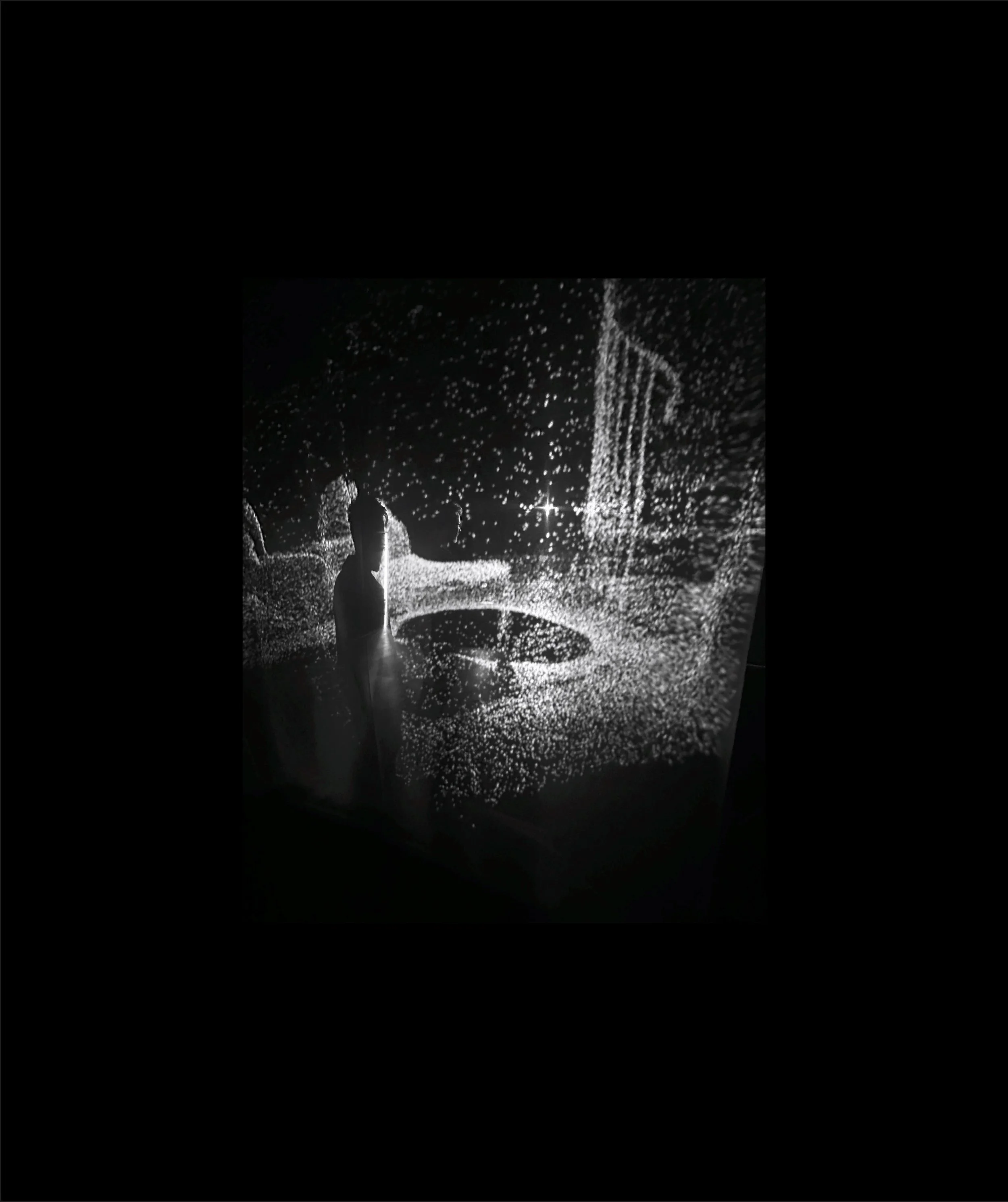 Children playing under a leafless tree during snowfall at night, illuminated by a streetlamp.