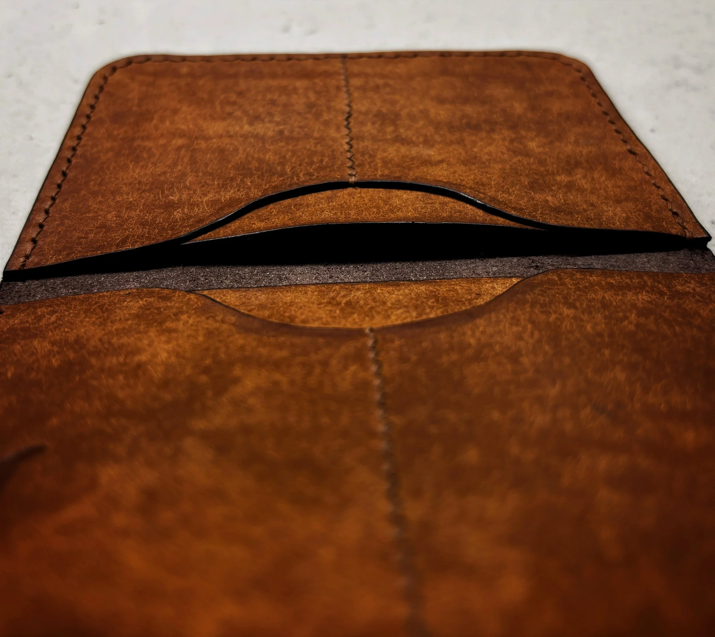 Close-up of a brown leather wallet with an open pocket on a flat surface.