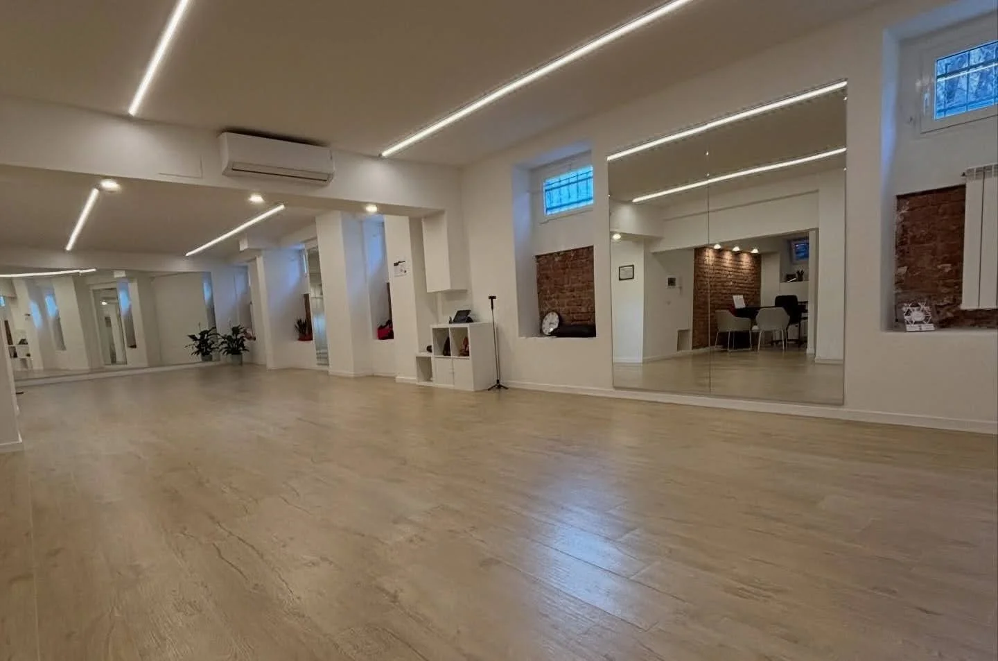 Sala da ballo ampia e luminosa con pavimento in parquet, specchi a parete e illuminazione a led moderna