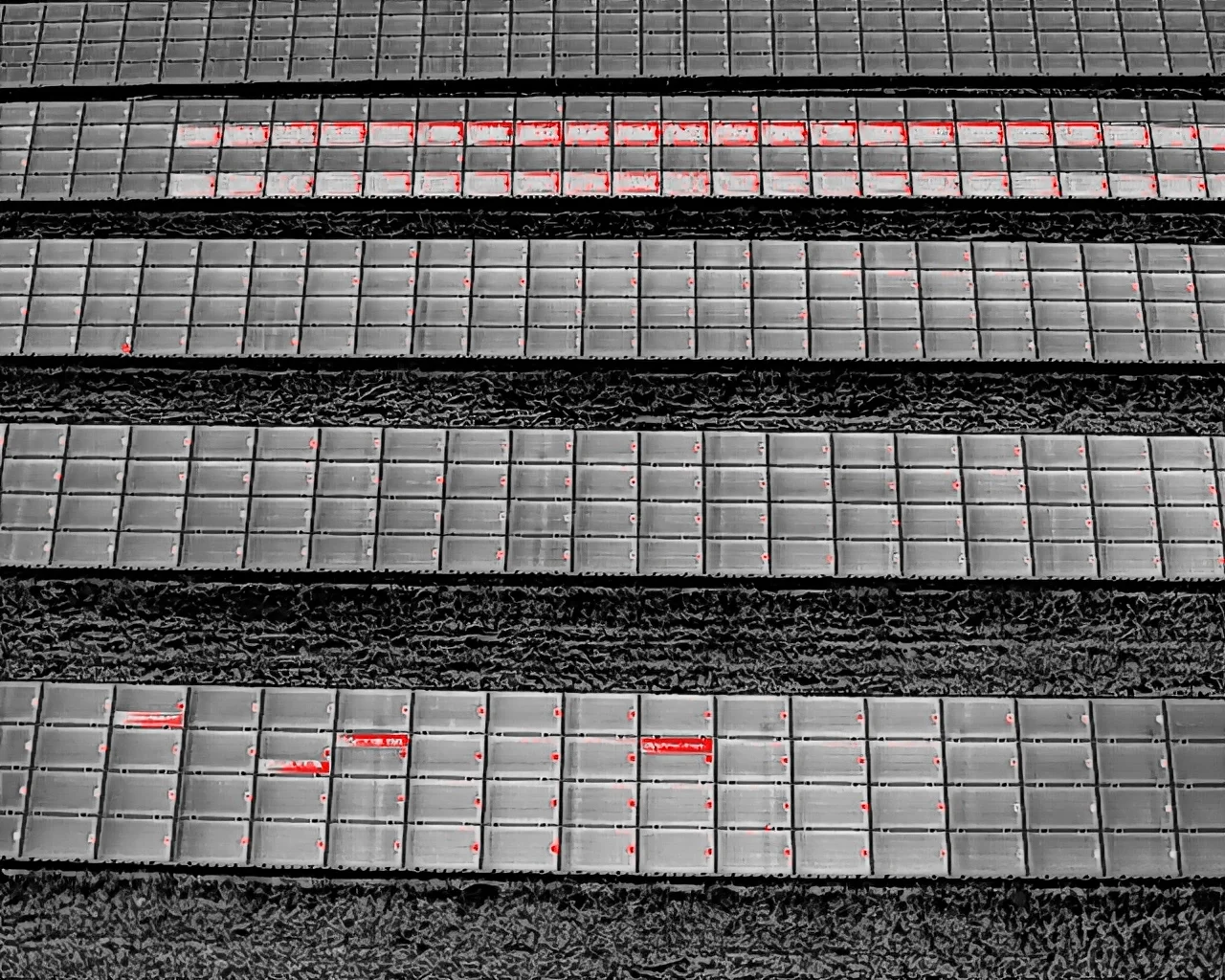 Aerial thermal imaging scan of a solar farm showing highlighted hotspots and cell defects in red.