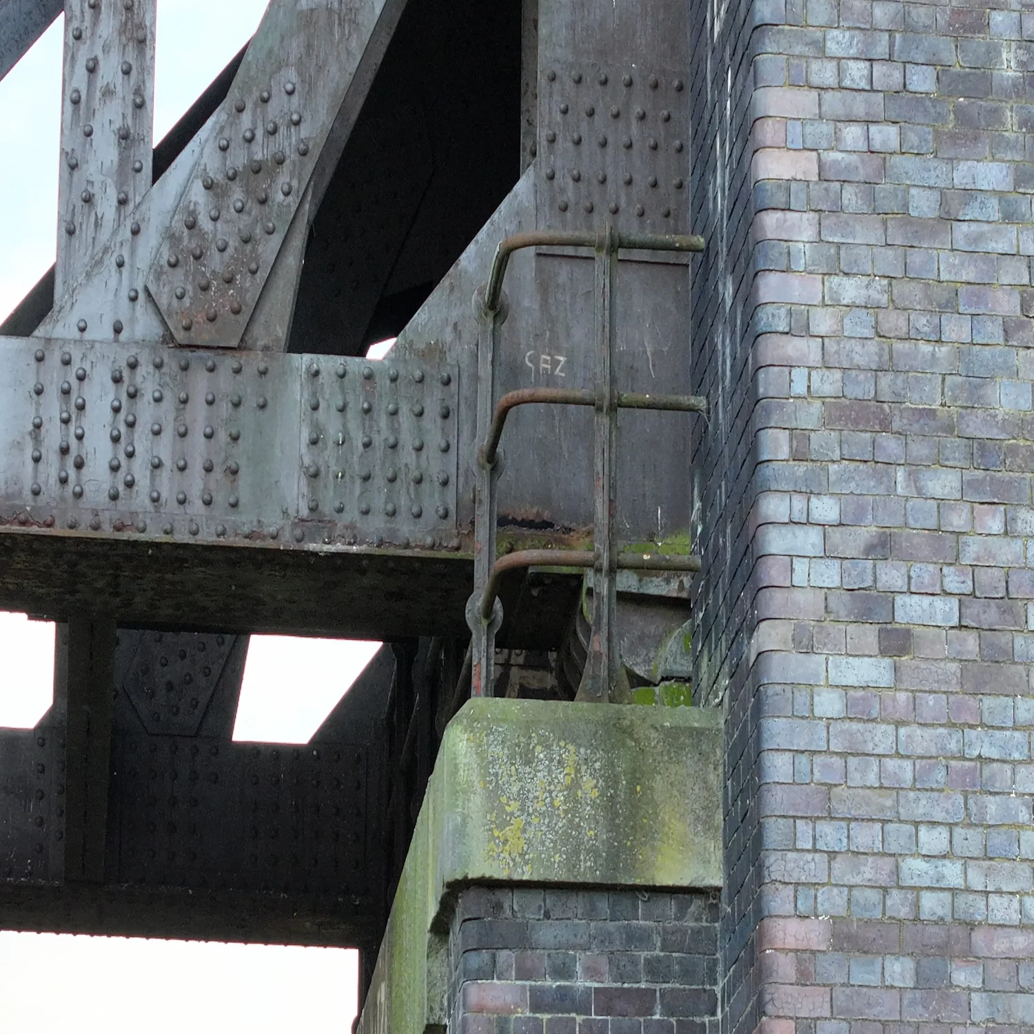 Aerial perspective of a weathered brick bridge abutment and steel support column captured by a GVC-certified drone pilot.
