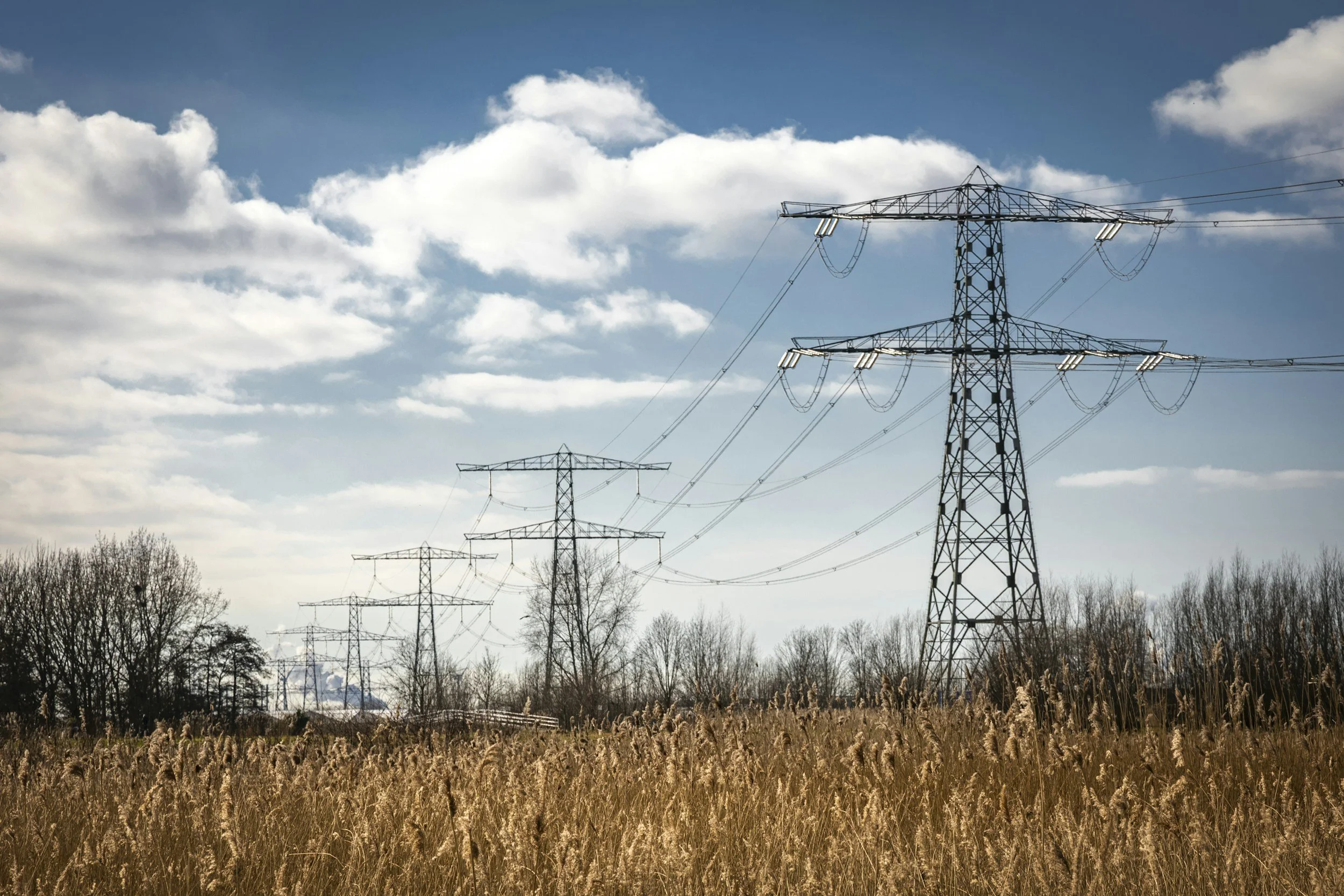 UAV inspection of a high-voltage transmission pylon and power lines in West Yorkshire. Using a 1,800m Laser Rangefinder and 112x zoom to identify cracked insulators, corrosion, and vegetation encroachment while maintaining a safe standoff distance fr