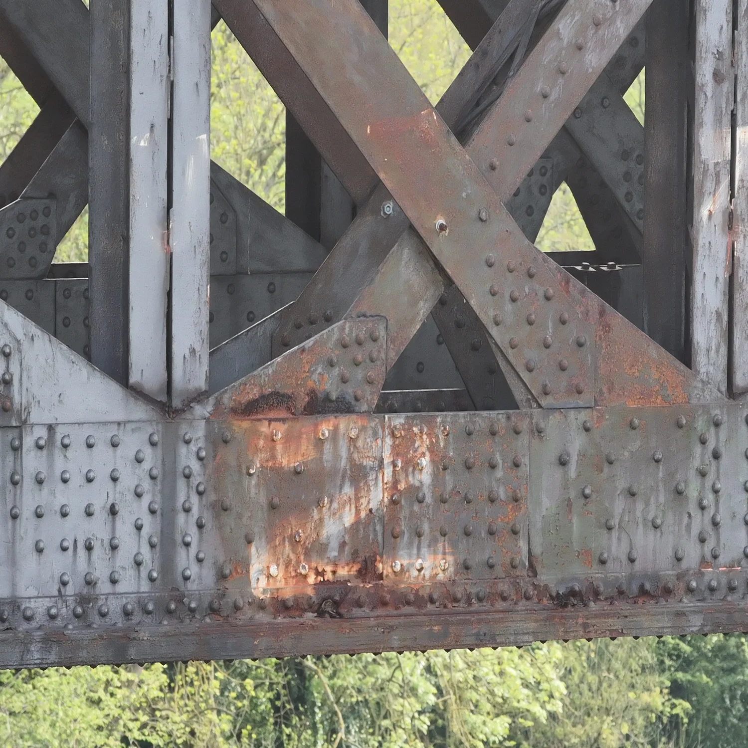 Detailed close-up of localized corrosion and rivet degradation on a steel bridge span. Utilizing advanced zoom capabilities, we provide clear visual data of structural concerns, ensuring safety and precision in infrastructure maintenance.