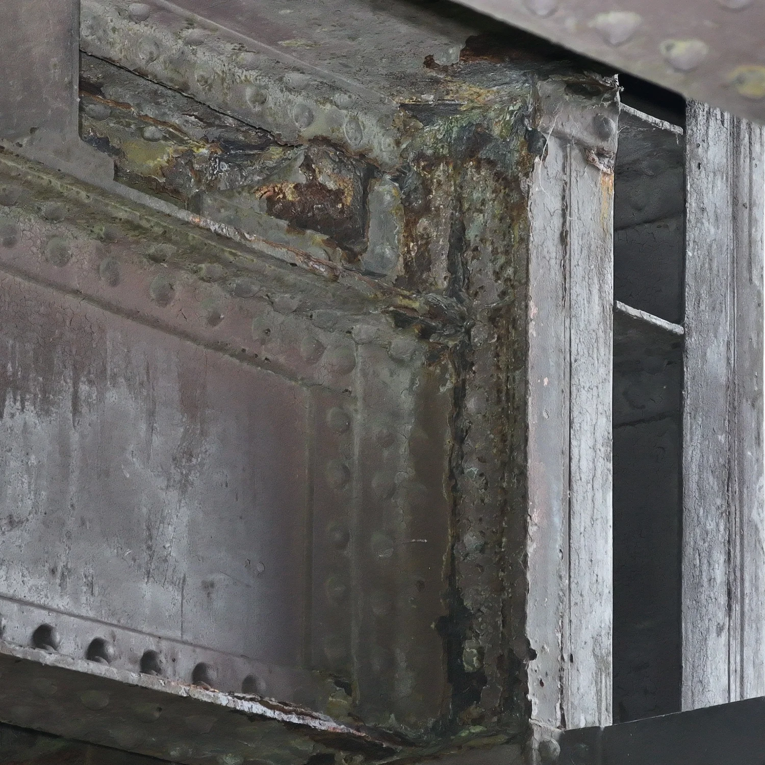Close-up technical drone image detailing surface corrosion and weathering on industrial bridge infrastructure.