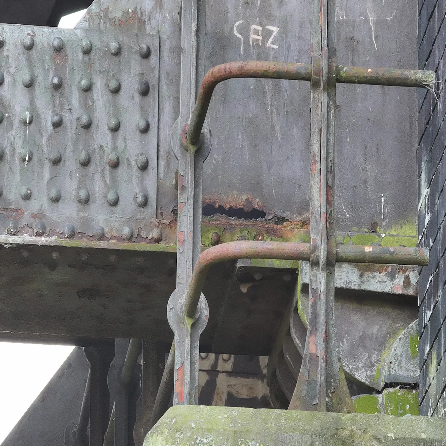 High-resolution 48MP drone photo of localized corrosion and rust on a steel bridge support joint and handrail for maintenance planning.