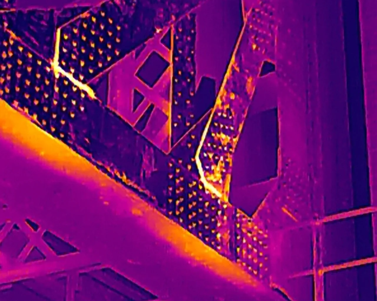 Thermal drone inspection of a steel bridge truss using the IronRed palette to identify heat signatures and potential structural anomalies.