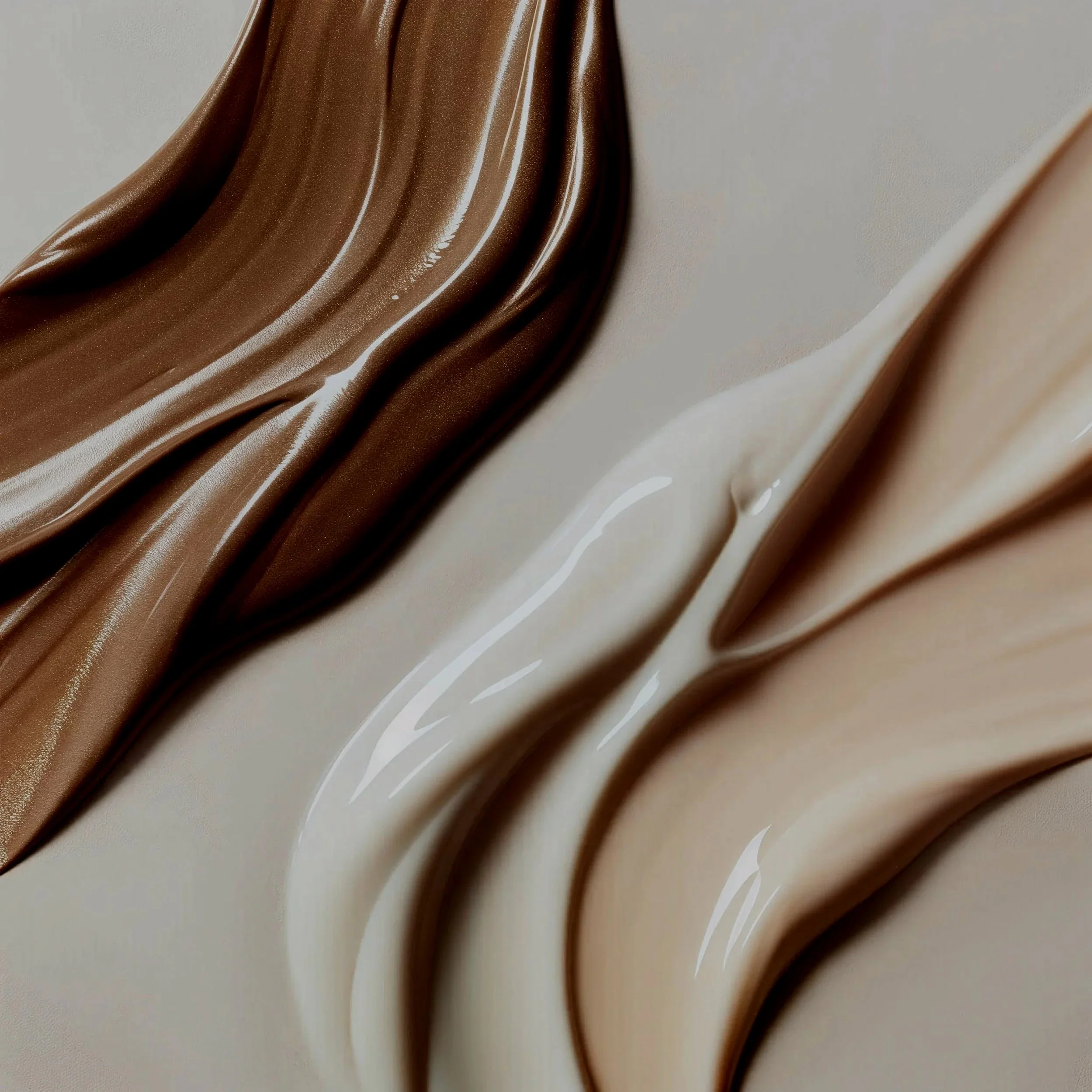 Close-up of three flowing streaks of creamy liquid in shades of brown, beige, and white.