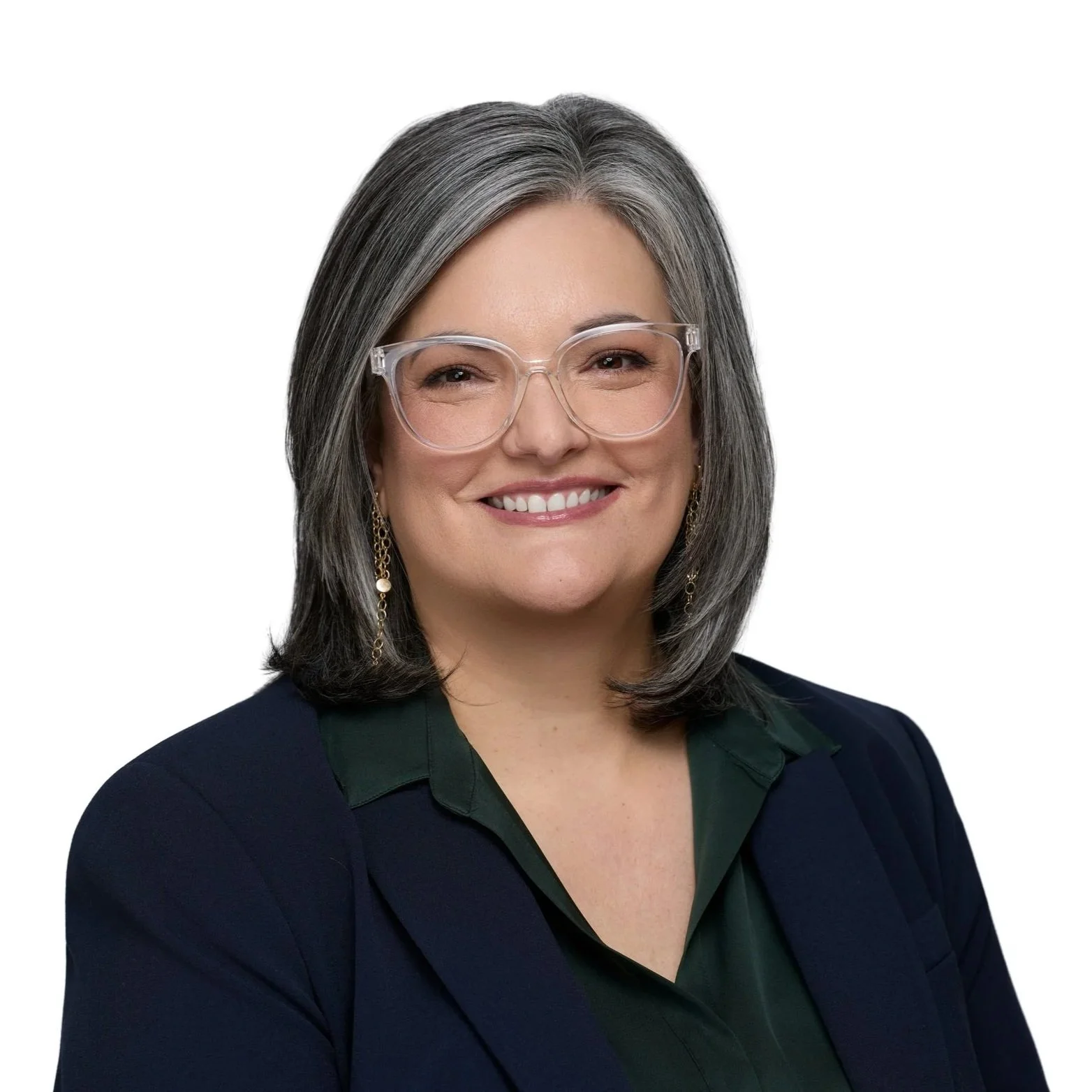 A woman with shoulder-length gray hair, wearing glasses, smiling, dressed in a dark blazer over a green blouse.