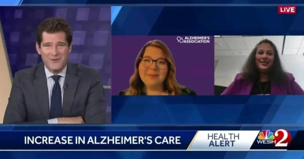 News broadcast featuring a male anchor and two women being interviewed remotely about the increase in Alzheimer's care. The background includes a purple Alzheimer's Association logo and a WESH 2 News banner.