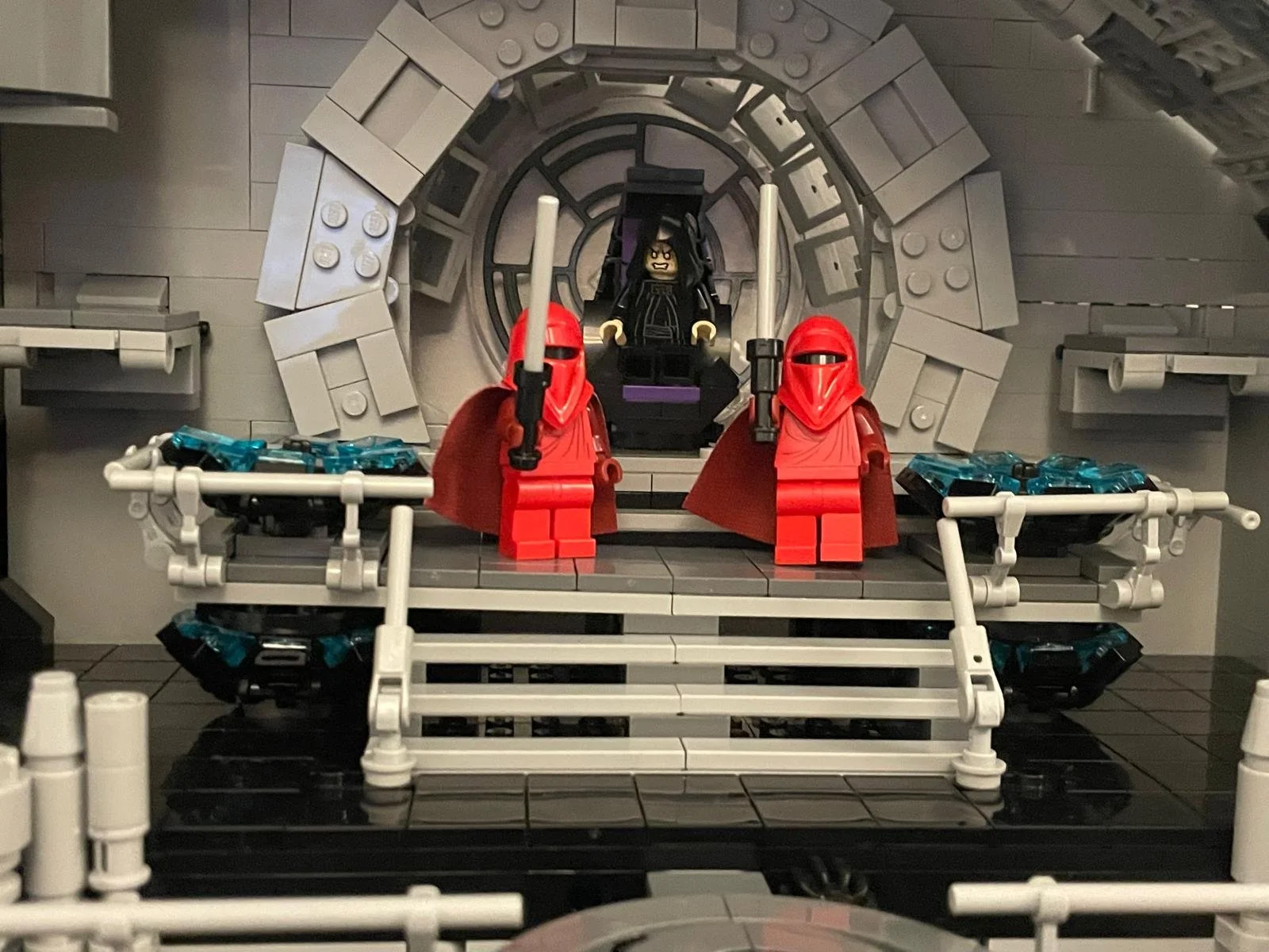 LEGO diorama of a scene with two red-robed figures holding swords on a staircase, with a sinister figure seated in a chair behind them, set in a futuristic or sci-fi environment.