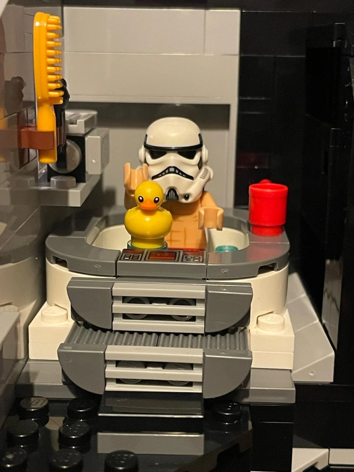 LEGO Star Wars scene with a stormtrooper helmet, a rubber yellow duck, toilet, and various LEGO pieces.