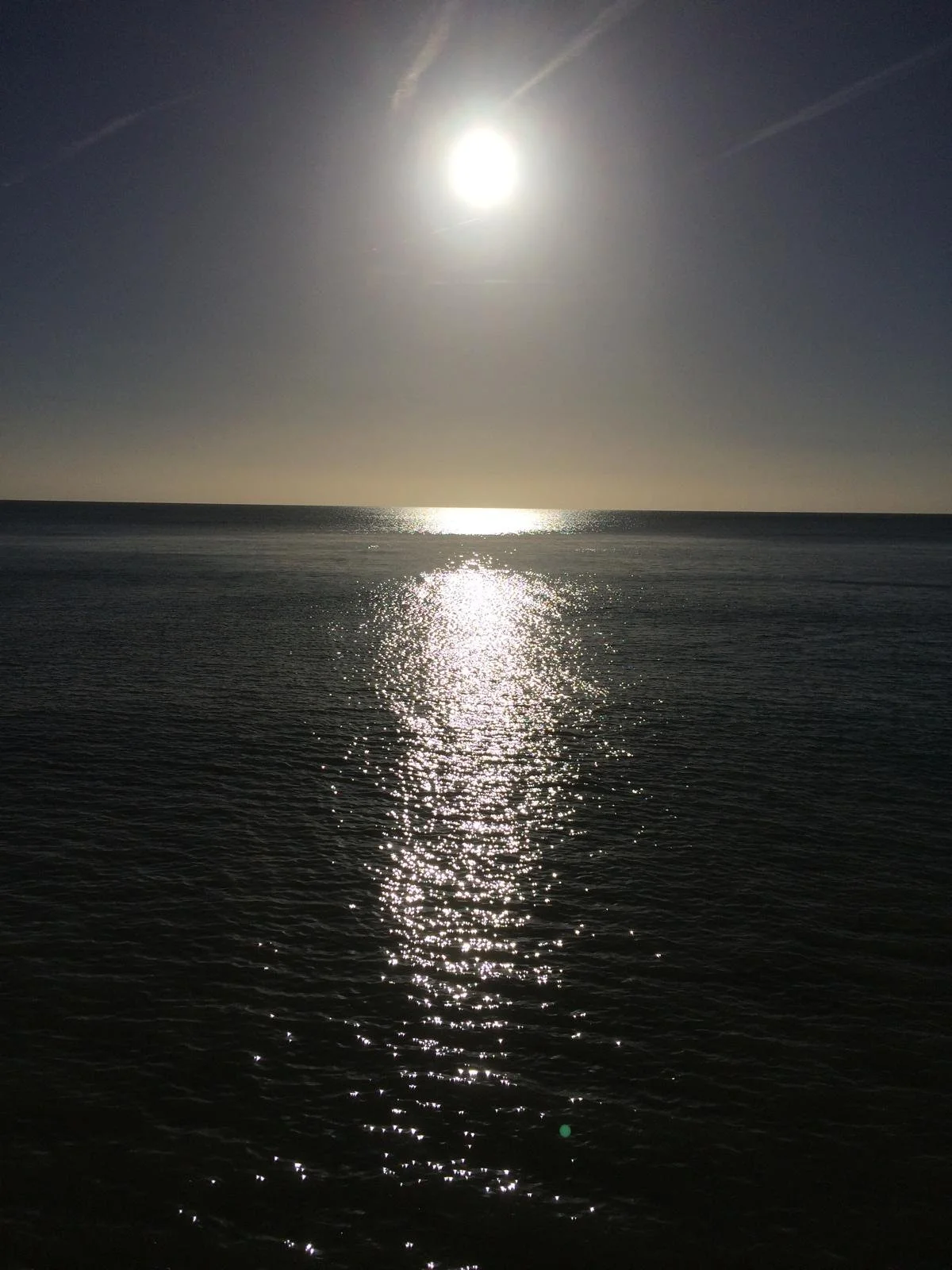 Sun reflecting on the ocean at sunset or sunrise with a clear sky.